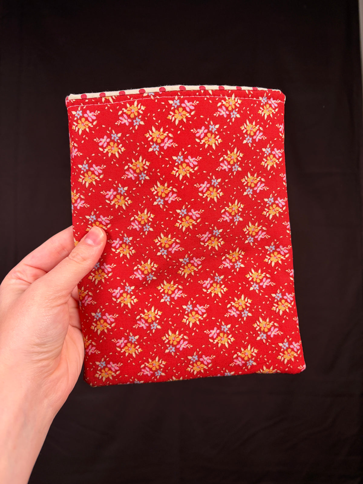 Red e-reader sleeve with gold-and-white holly print, flat front view