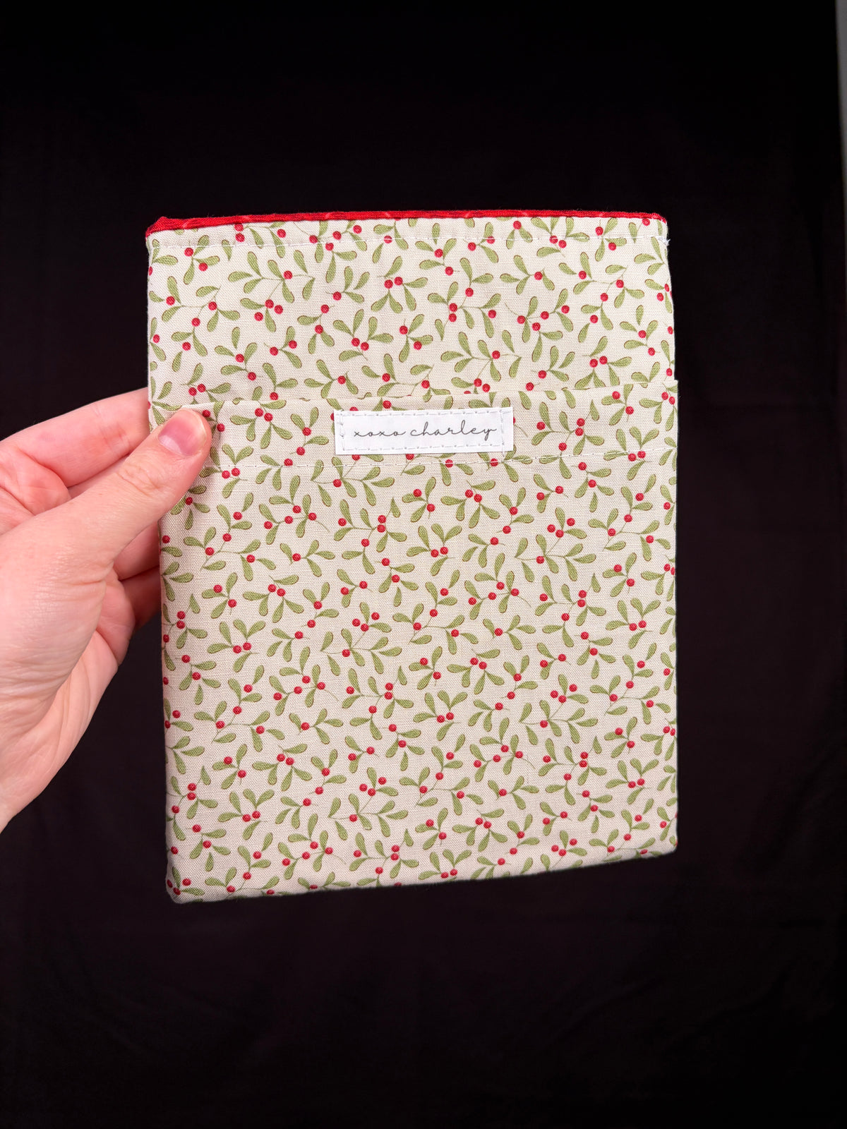 Cream e-reader sleeve with red-green floral pattern and centered label