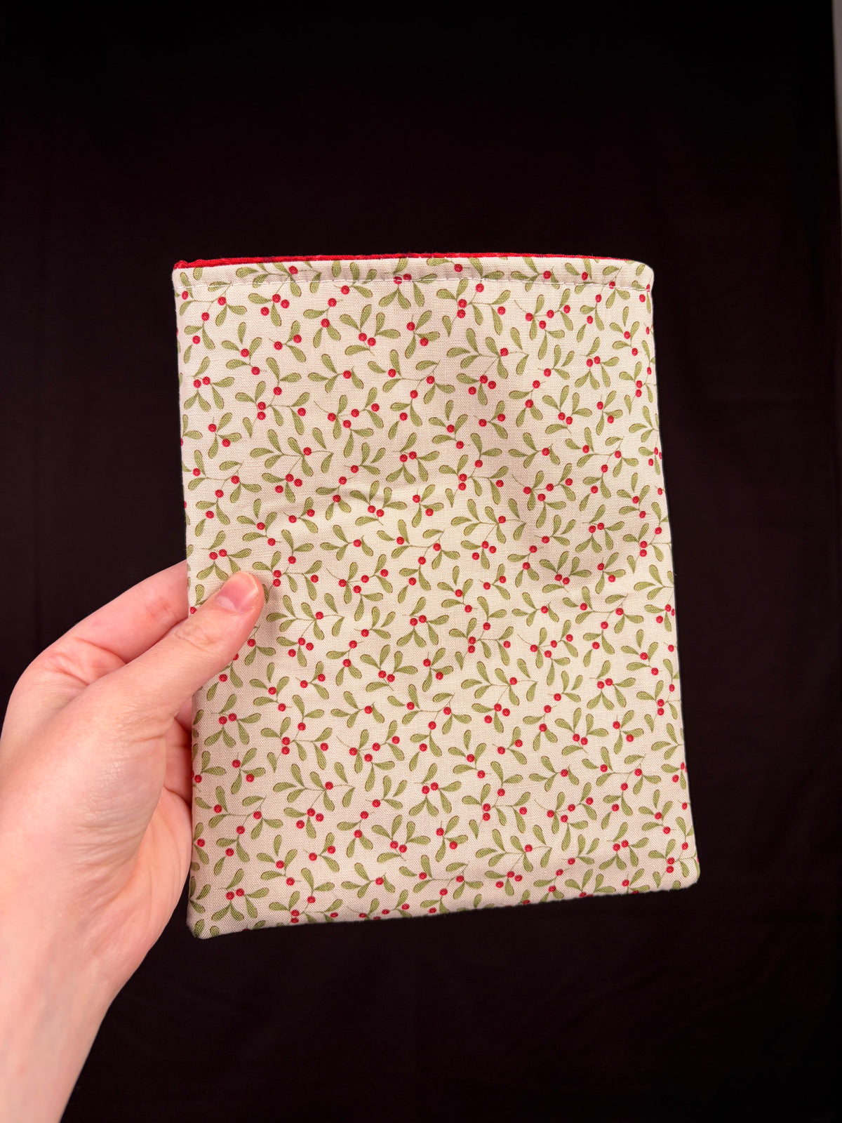 Cream e-reader sleeve with red-green floral pattern, flat back view
