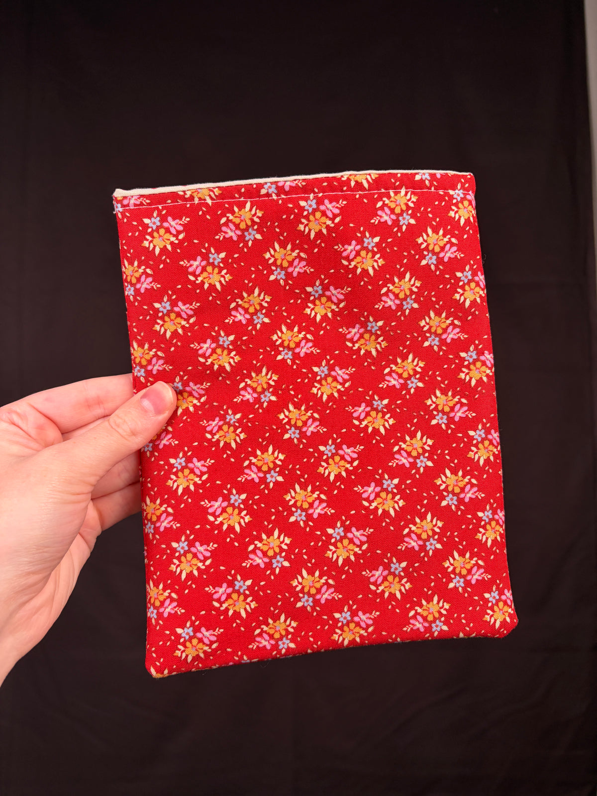 Red e-reader sleeve with all-over yellow floral print, plain back panel