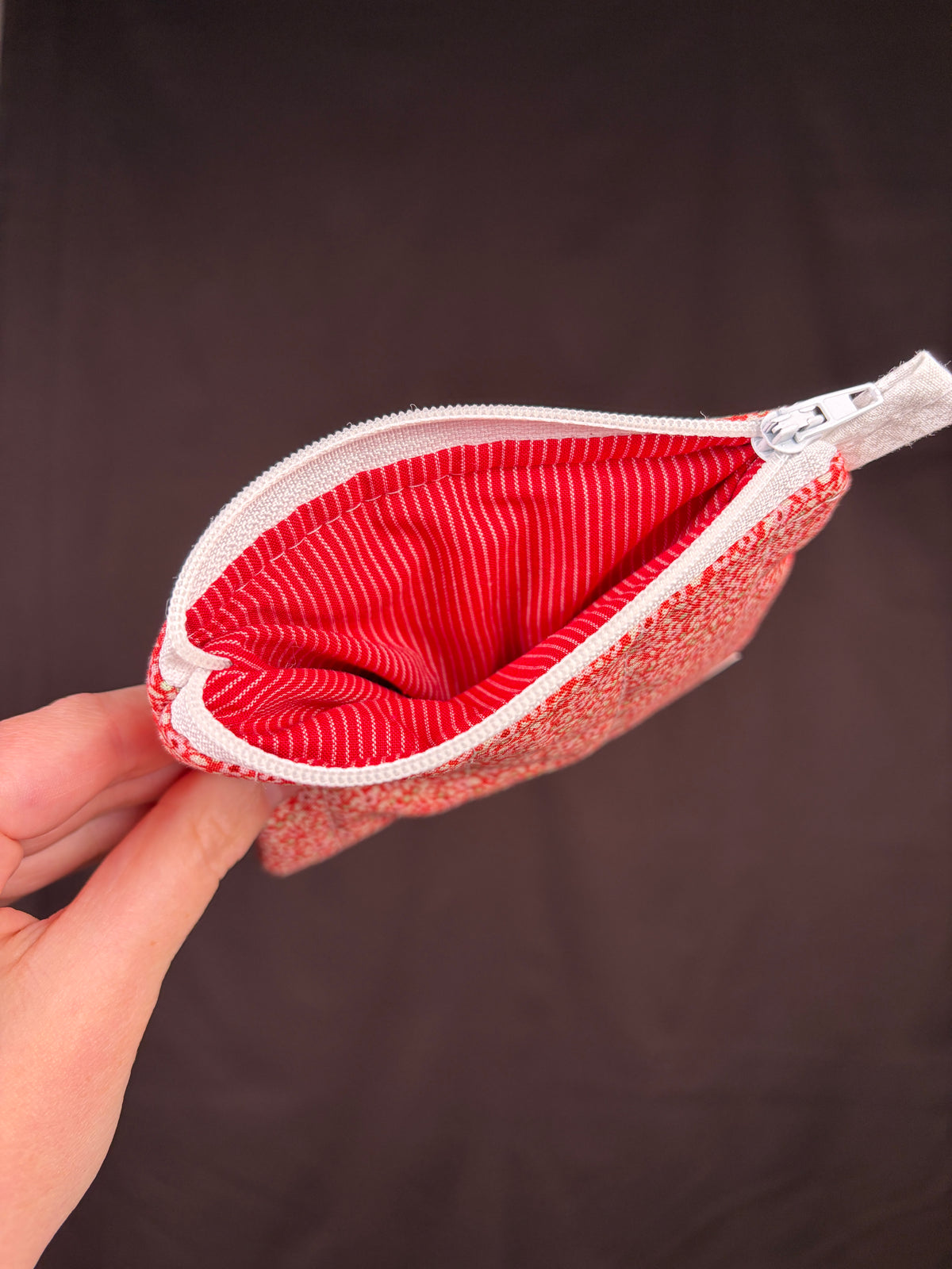 Red glitter keychain wallet opened to show red striped interior and zipper