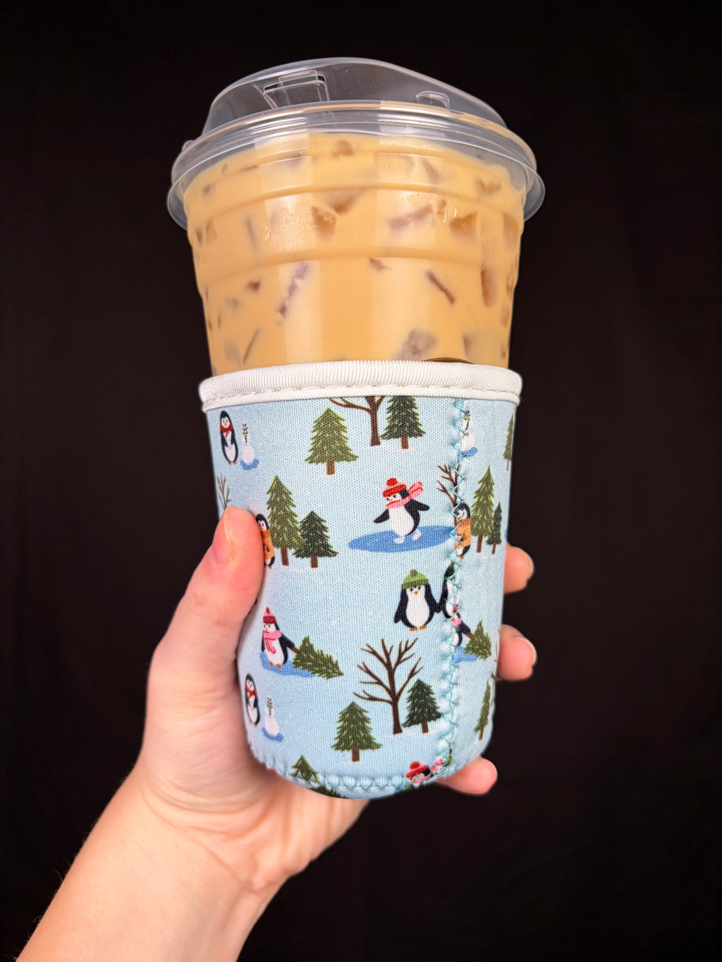 Small cup sleeve with blue winter scene, penguins, and pine trees