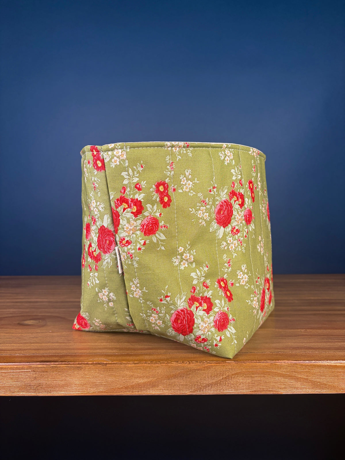 Large fabric bowl with red rose floral print on light green fabric, side view