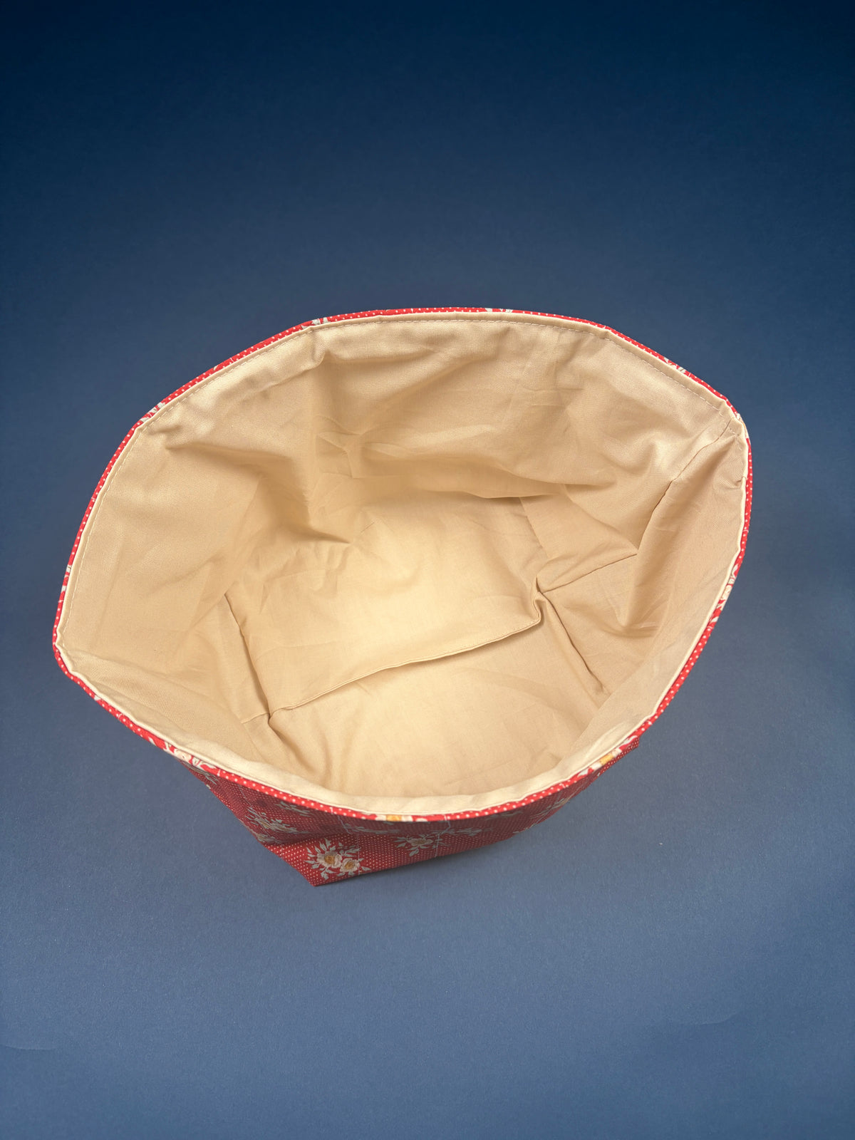 Large fabric bowl with beige fabric lining, red patterned exterior
