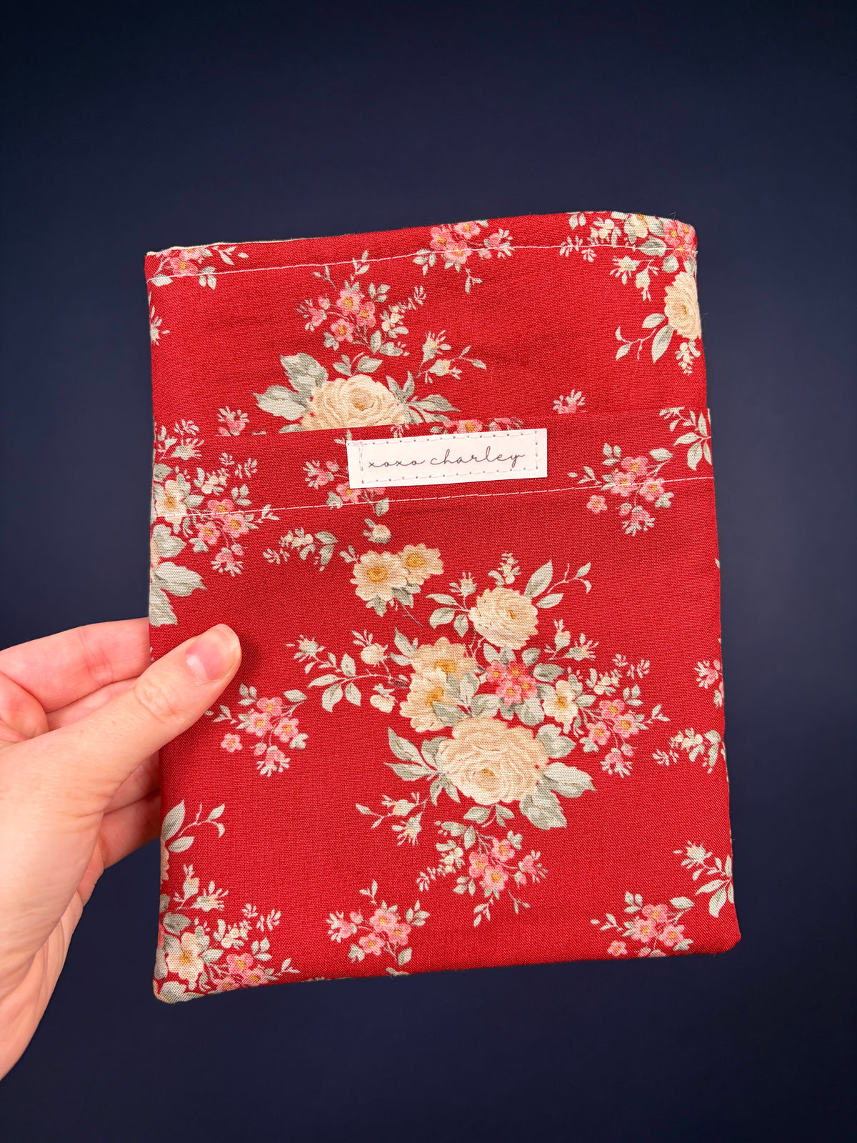 Red floral e-reader sleeve with fabric label at center front