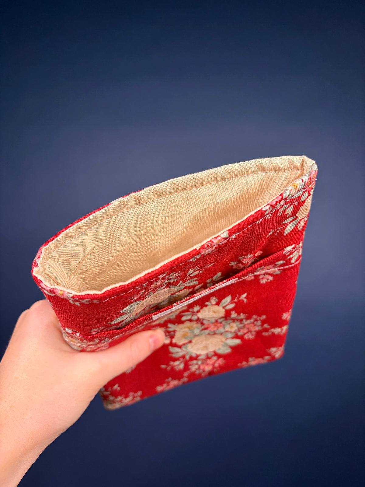 Red floral e-reader sleeve with visible tan lining and rounded side opening