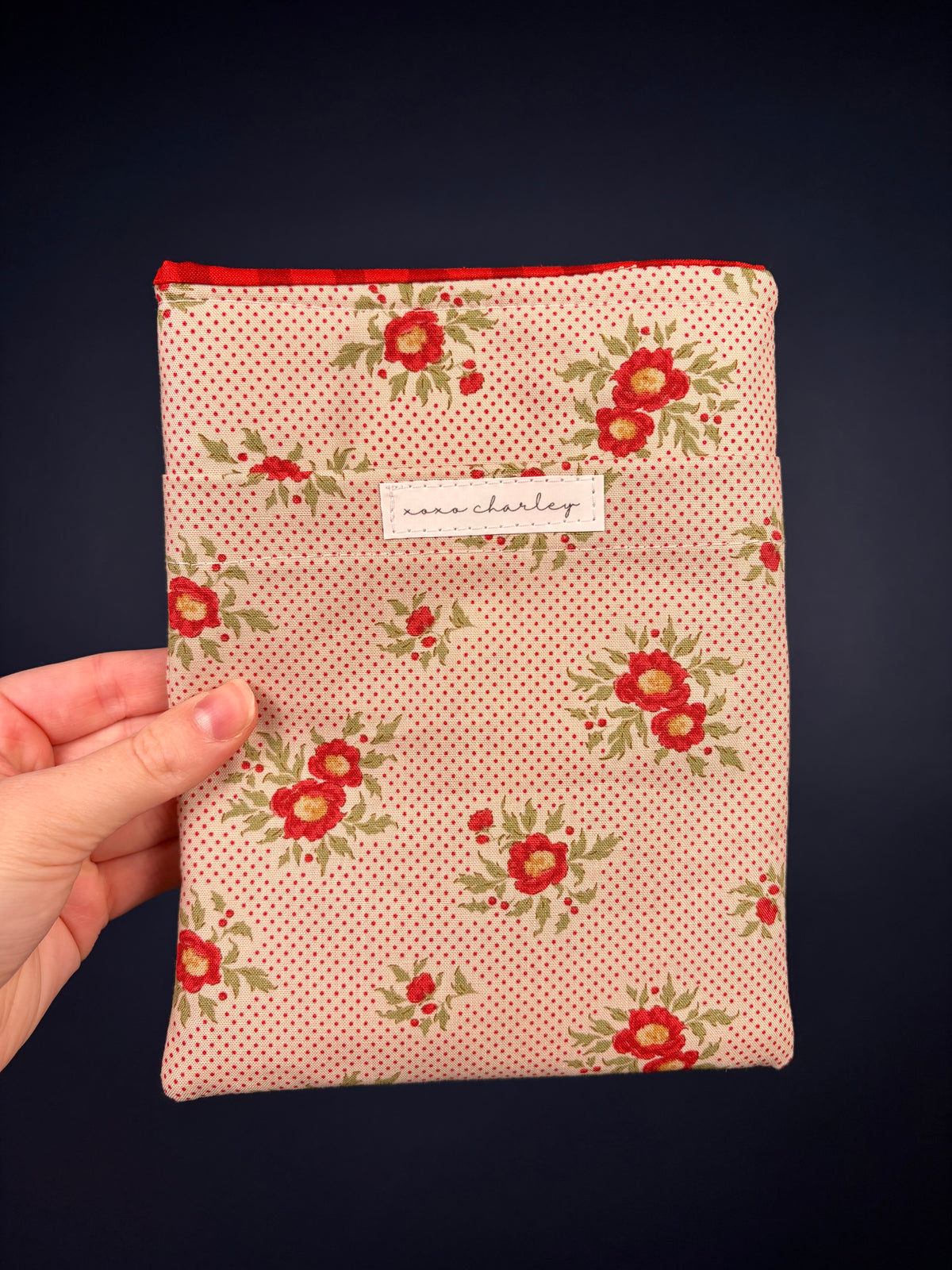 Floral e-reader sleeve with pink polka dots and red flowers, with front label patch