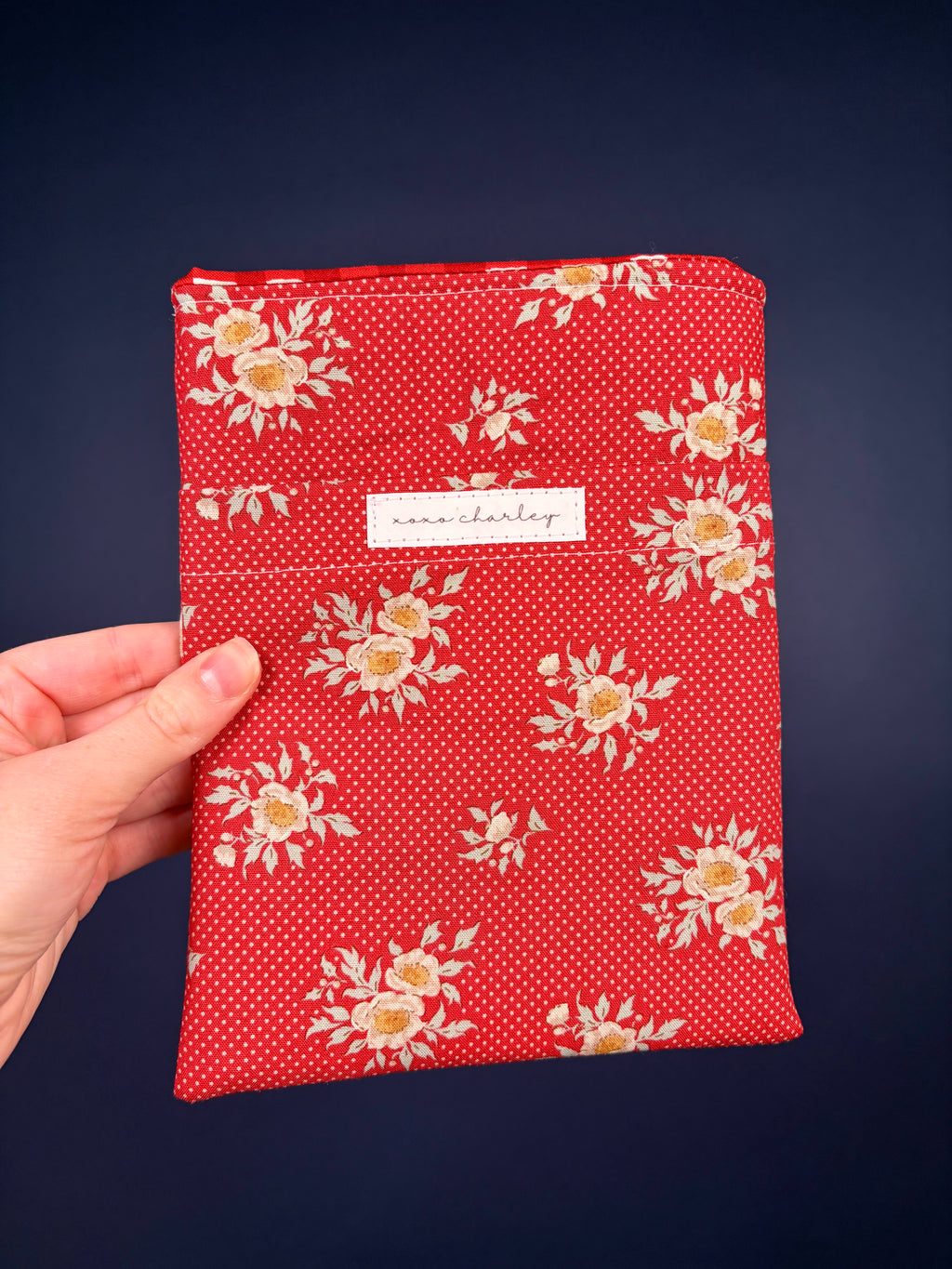 Red e-reader sleeve with floral and polka-dot pattern, ribbon tie and center label