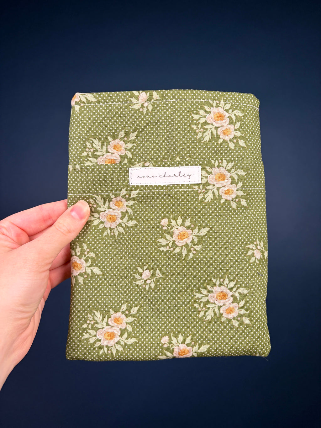 Olive e-reader sleeve with white floral pattern and fabric label