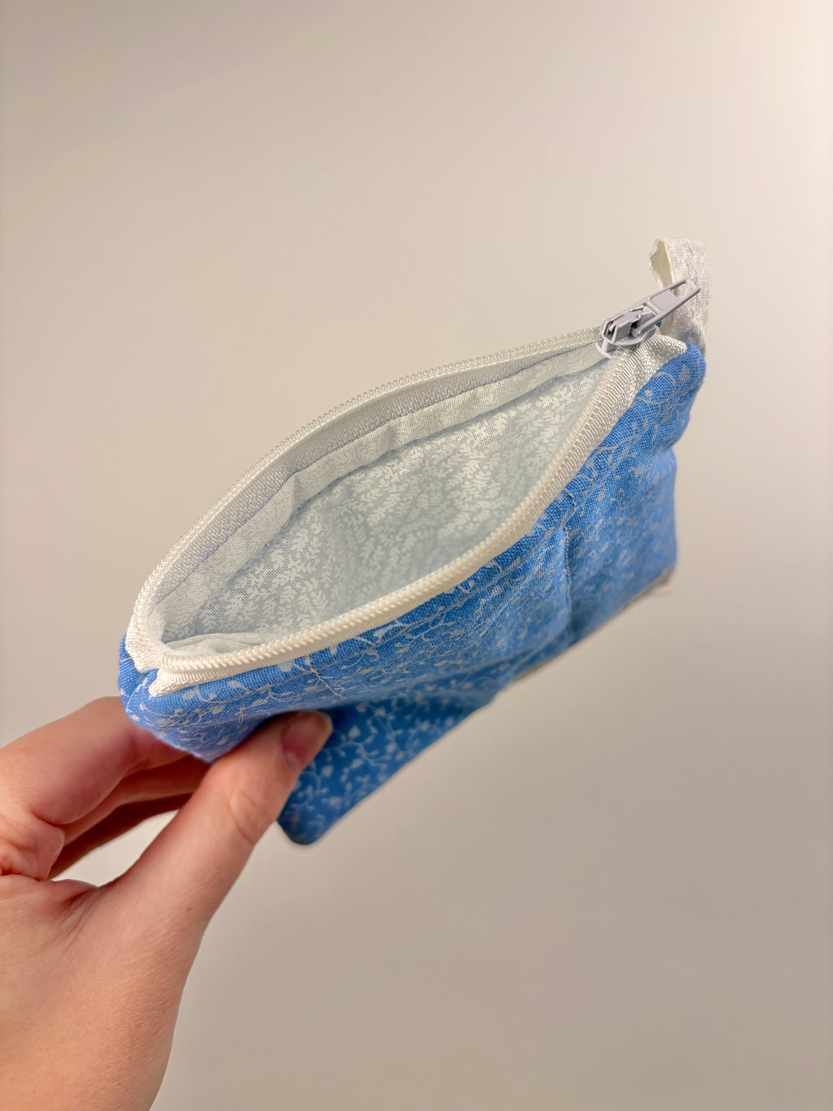 Blue keychain wallet with white hearts, zipper-open interior view, fabric lining