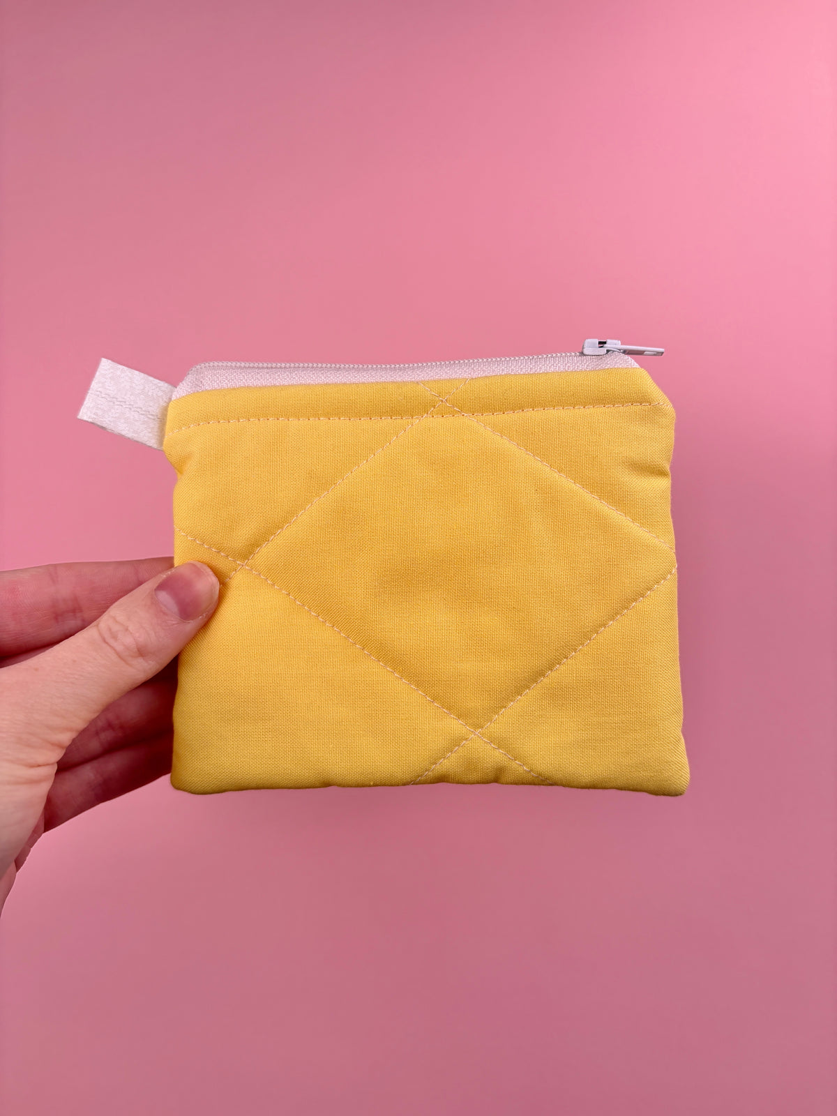 Yellow quilted keychain wallet with zip closure, stitched front, and fabric pull