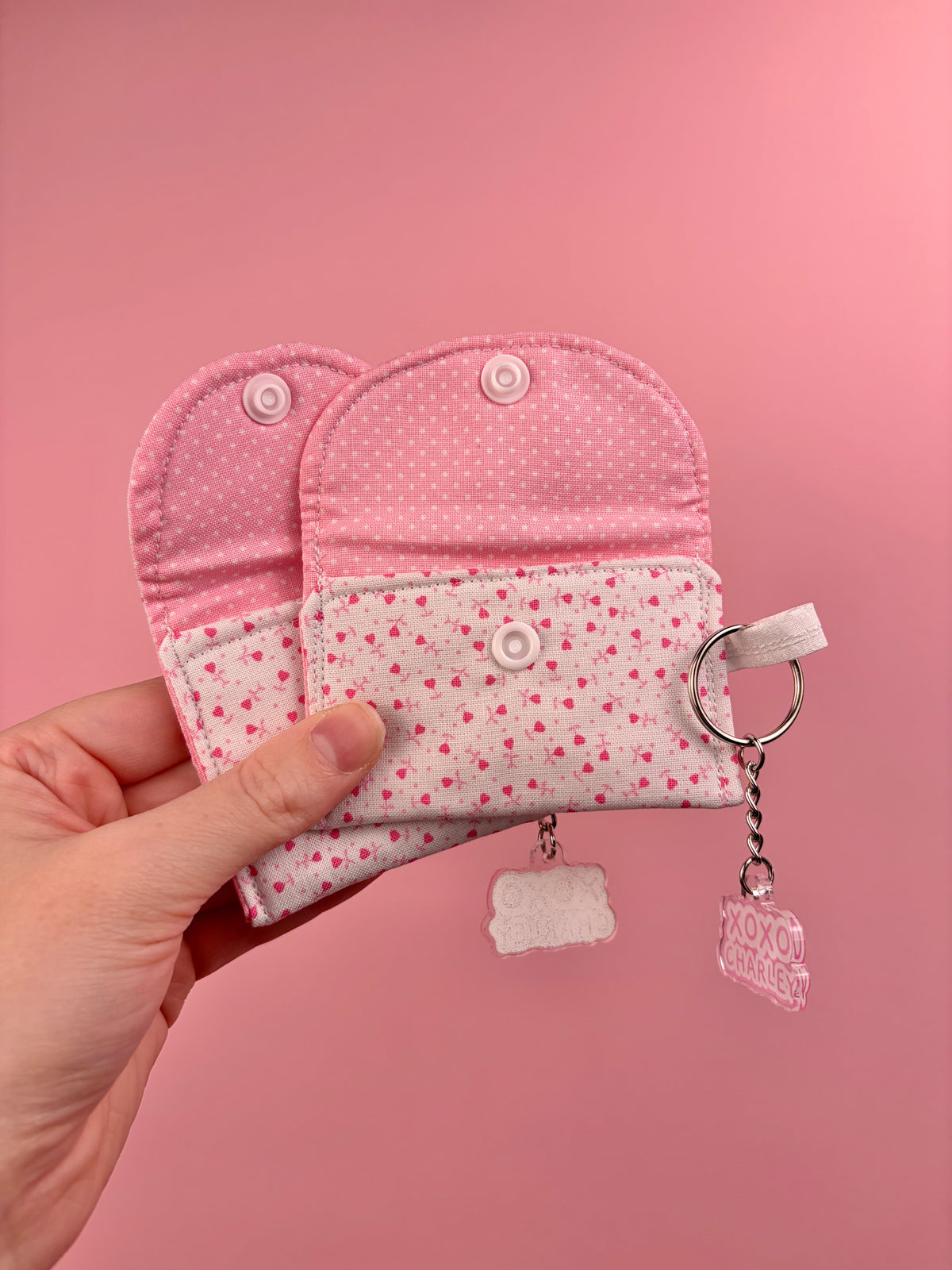 Pink heart-print earbuds case with snap flap closure and keychain charm