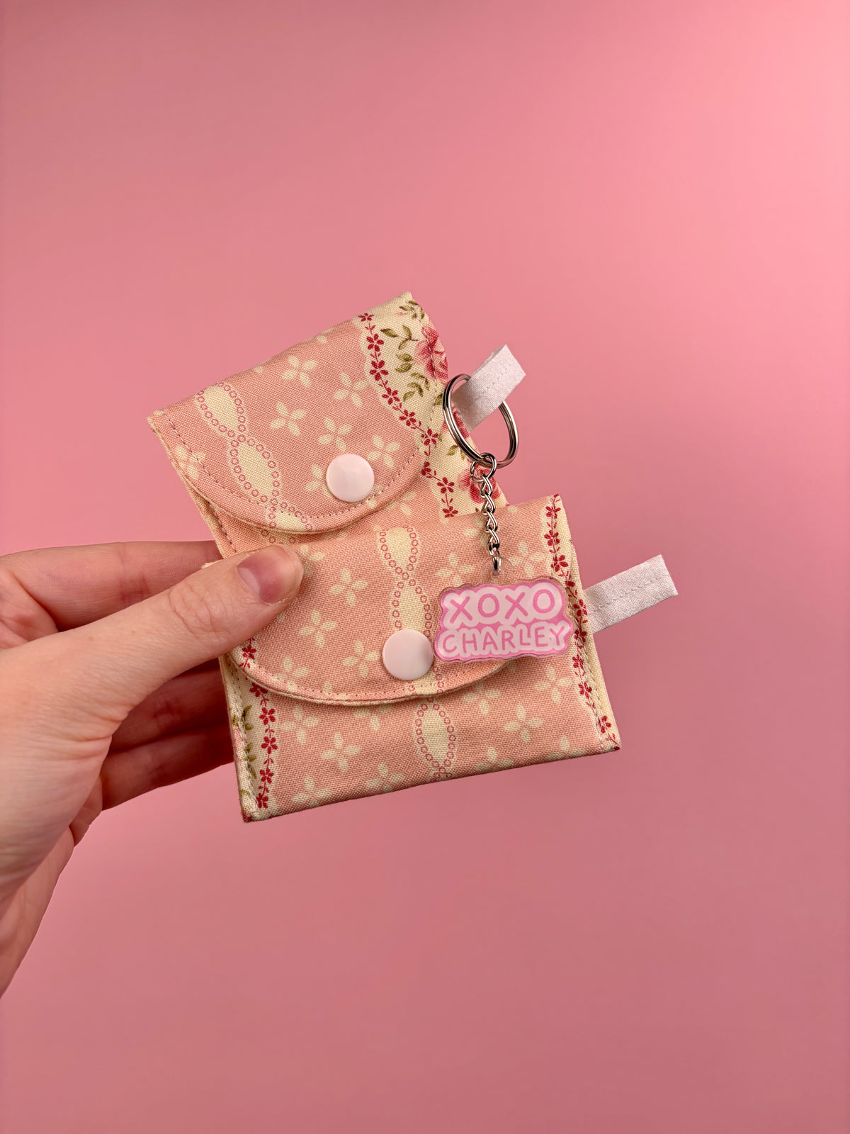 Floral earbuds case in pink and yellow with clips, keyring, and snap closure