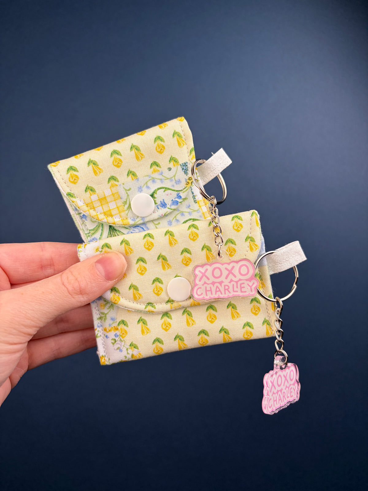 Patchwork earbuds case with green yellow leaf pattern and keyring charm, flap closure.