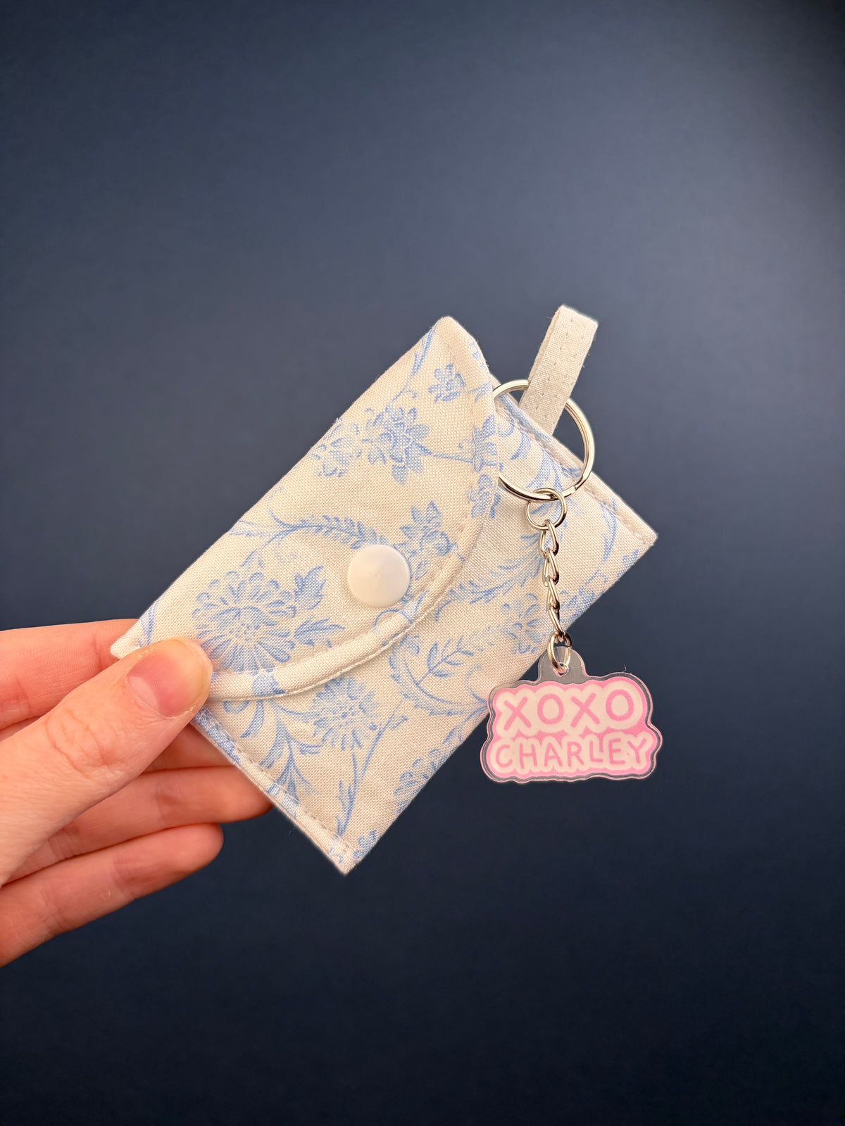 Blue floral earbuds case with snap and clip; XOXO charm with dangling tags