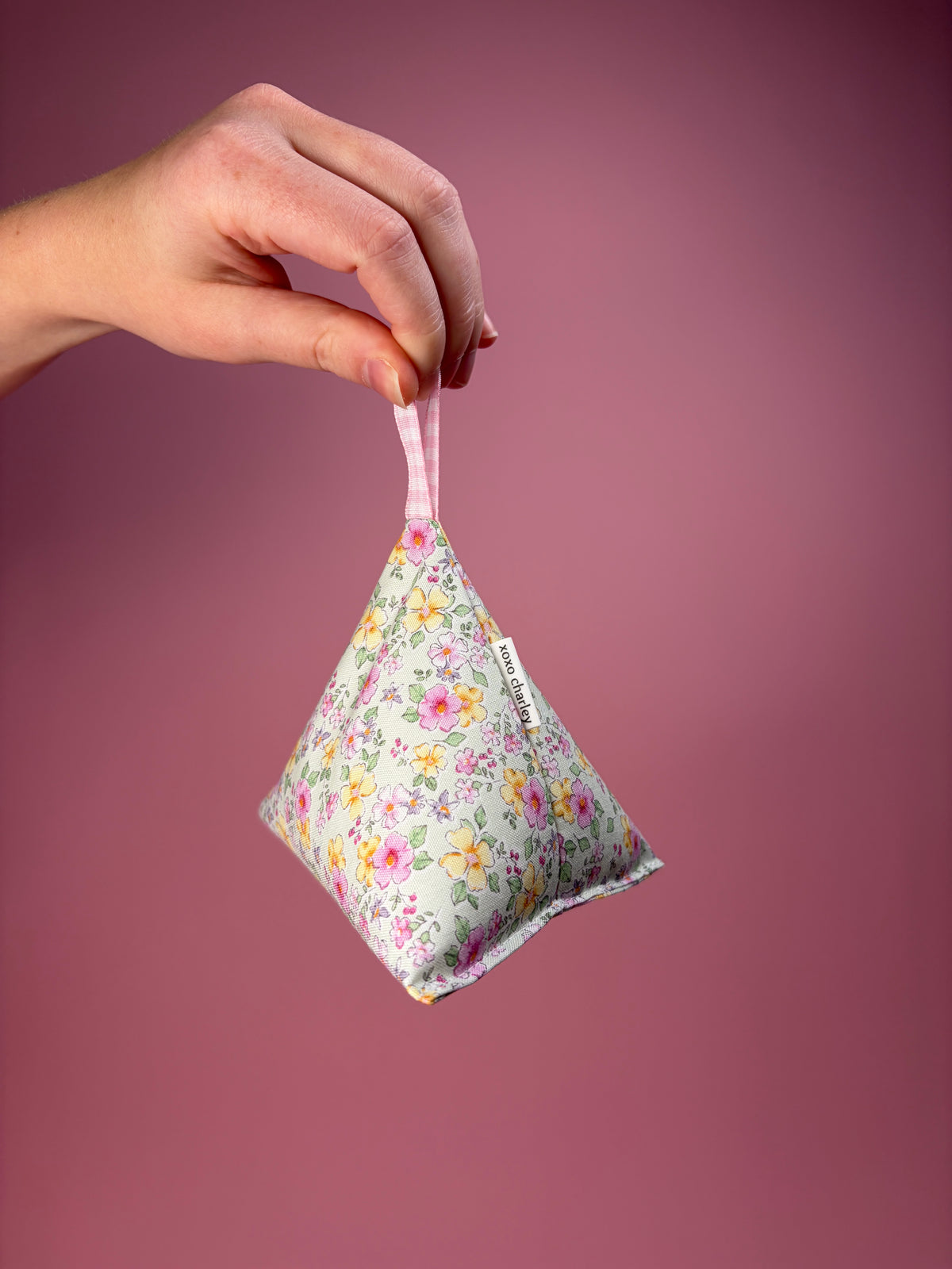 Floral fabric bag weight with pink ribbon, held in hand