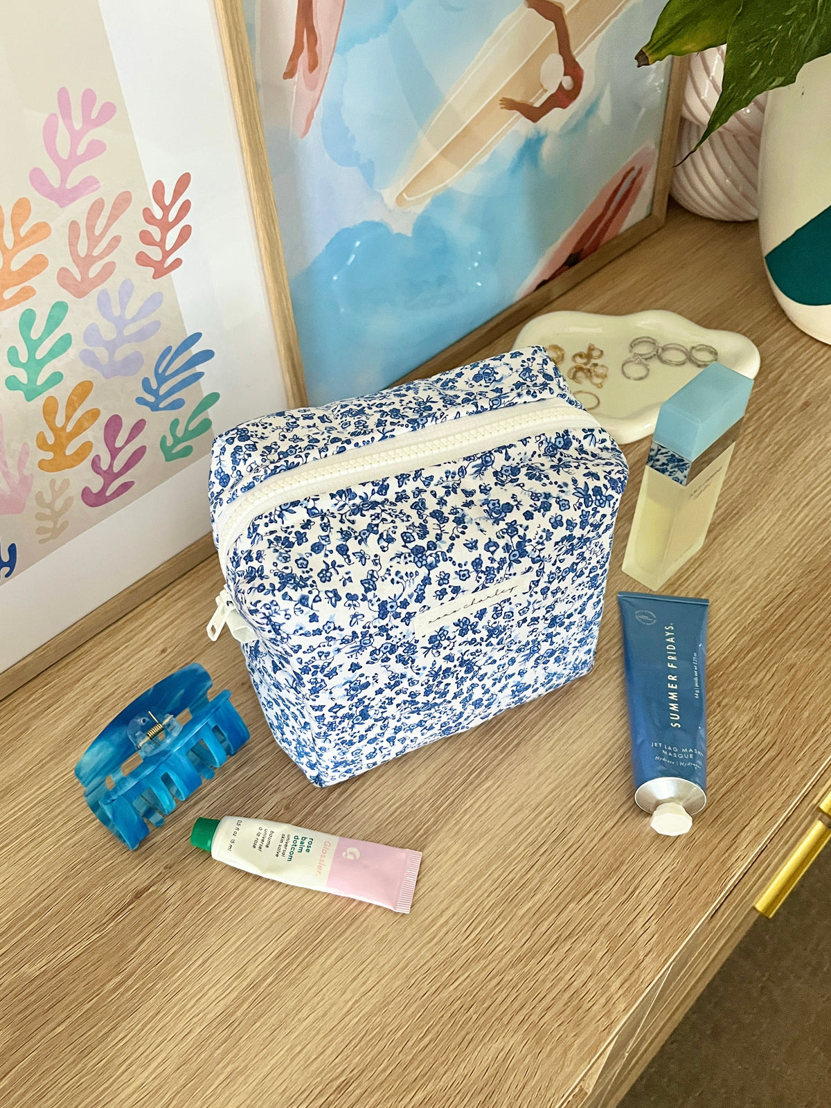 Medium makeup bag with blue floral print, front view and curved white zipper