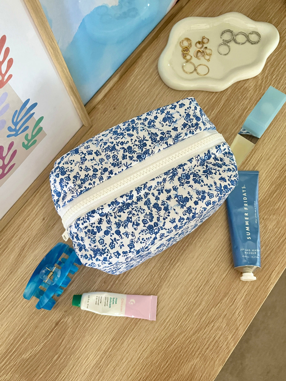 Medium makeup bag with blue floral print and white zipper panel, side angle
