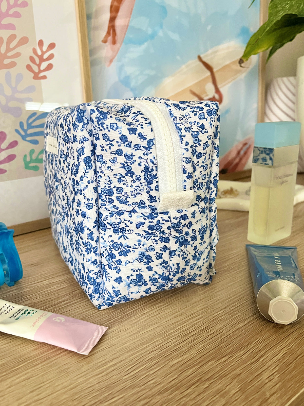 Medium makeup bag in blue floral print with top handle and white zipper