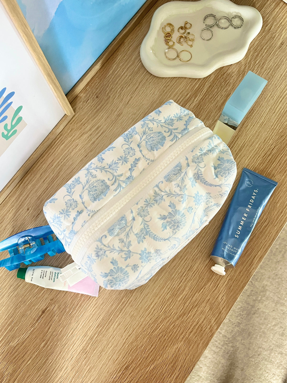 Light blue floral medium makeup bag on its side with zipper