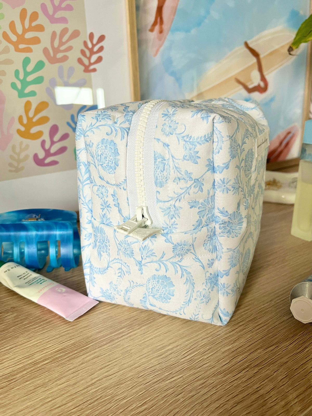 Light blue floral makeup bag with top handle and zipper front