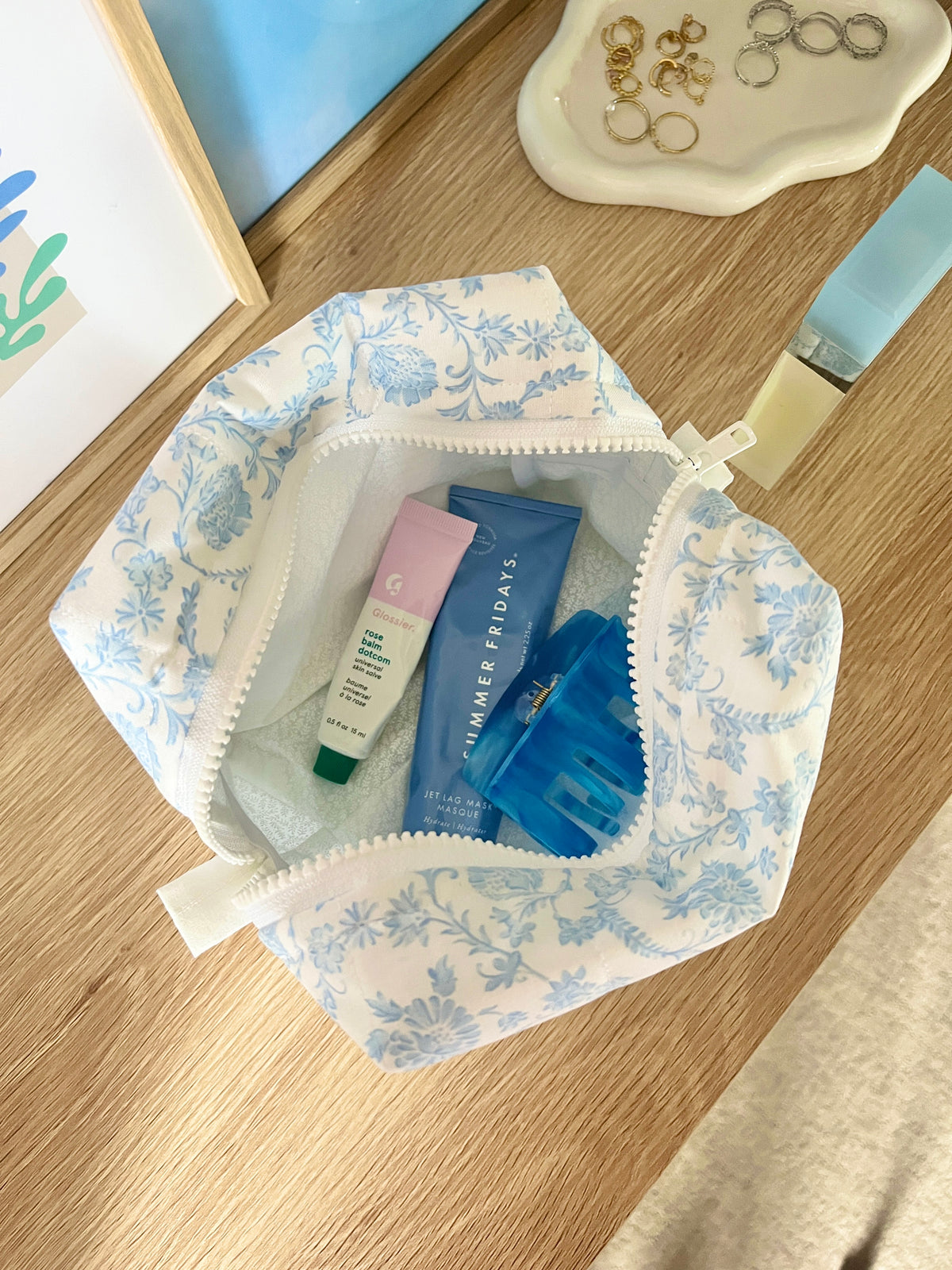 Light blue floral makeup bag opened, showing inner pockets and products