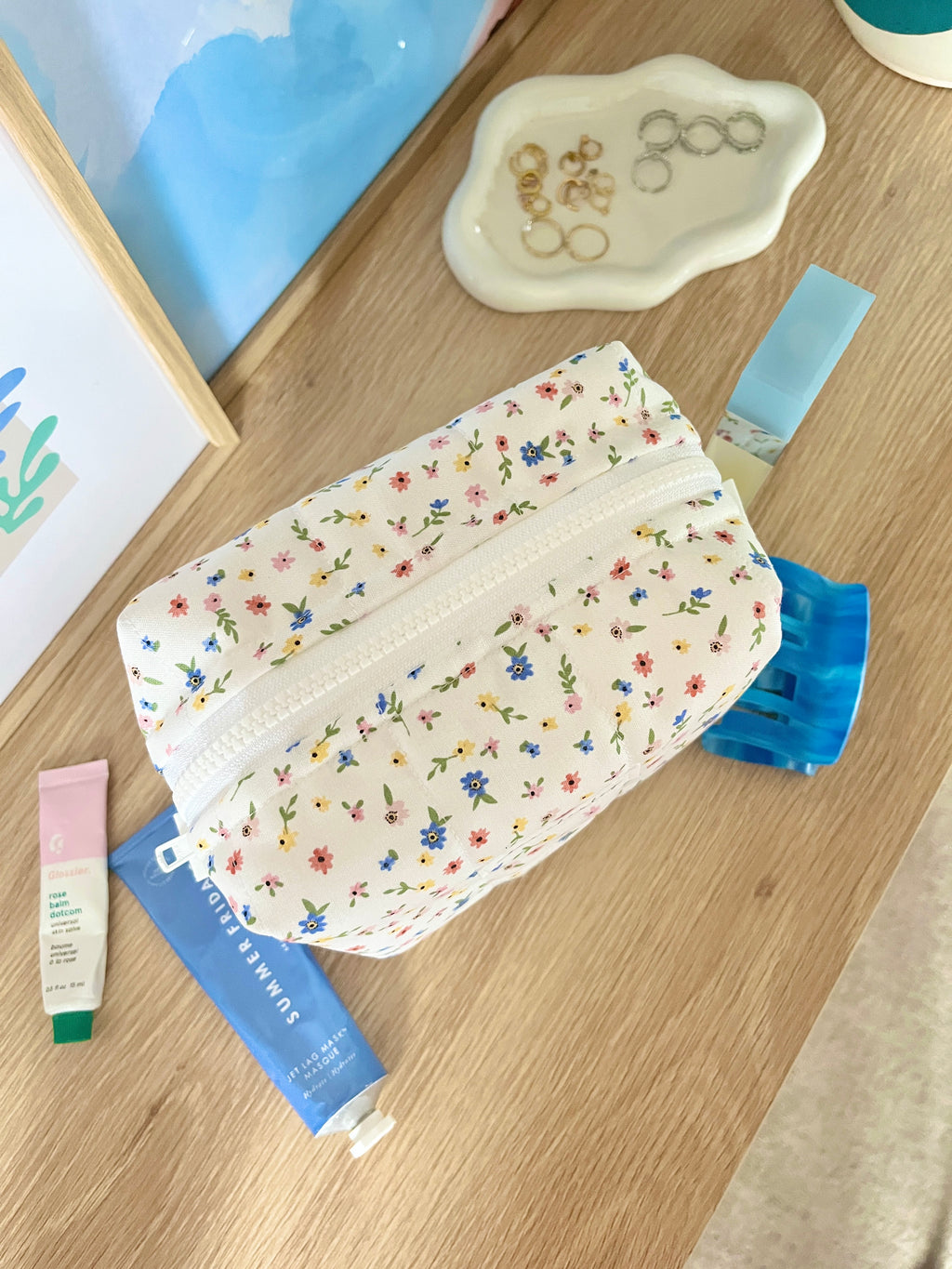Floral mini makeup bag with light blue trim, white zipper pouch, front view