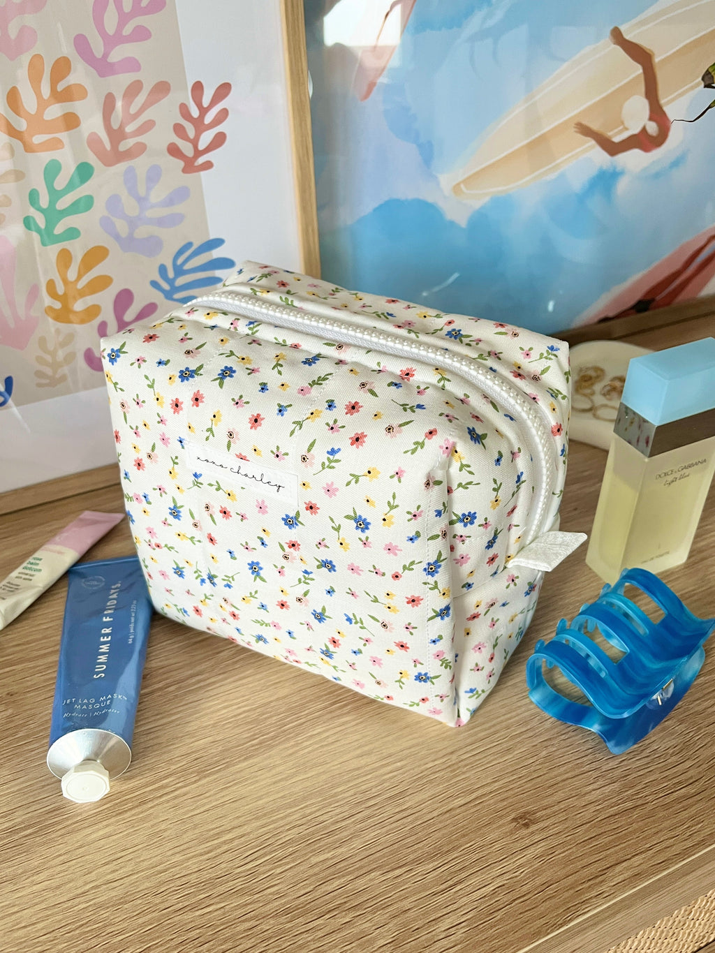Floral mini makeup bag with curved top zipper, white pouch, angled view