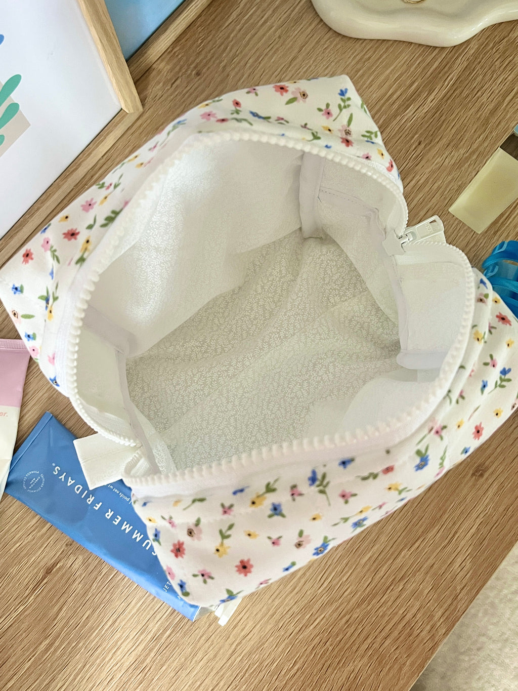 Open floral mini makeup bag, white interior lining, zipper pouch on display