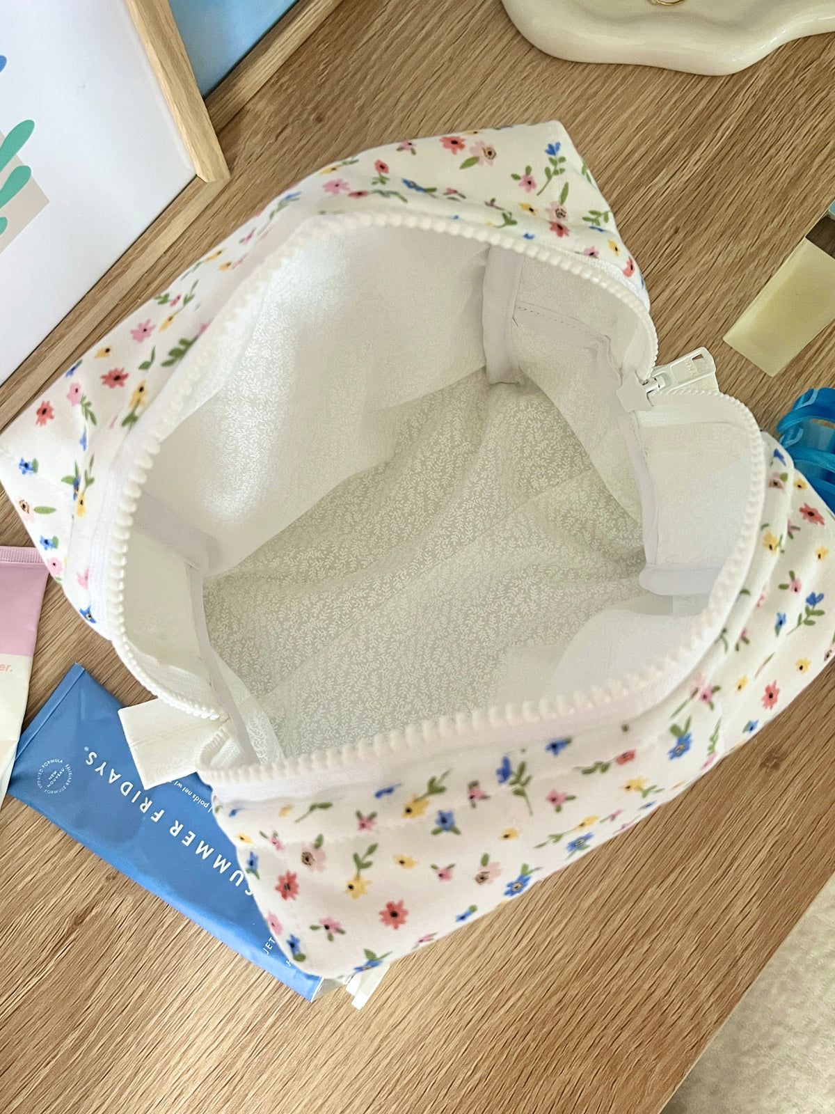 Open floral mini makeup bag, white interior lining, zipper pouch on display