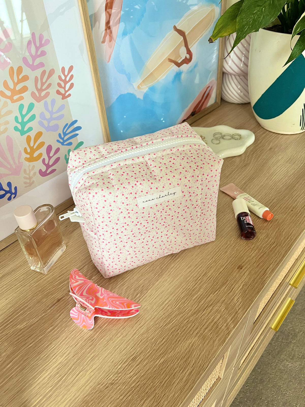 Medium makeup bag in pink with tiny heart print, zip-top and white zipper pull.