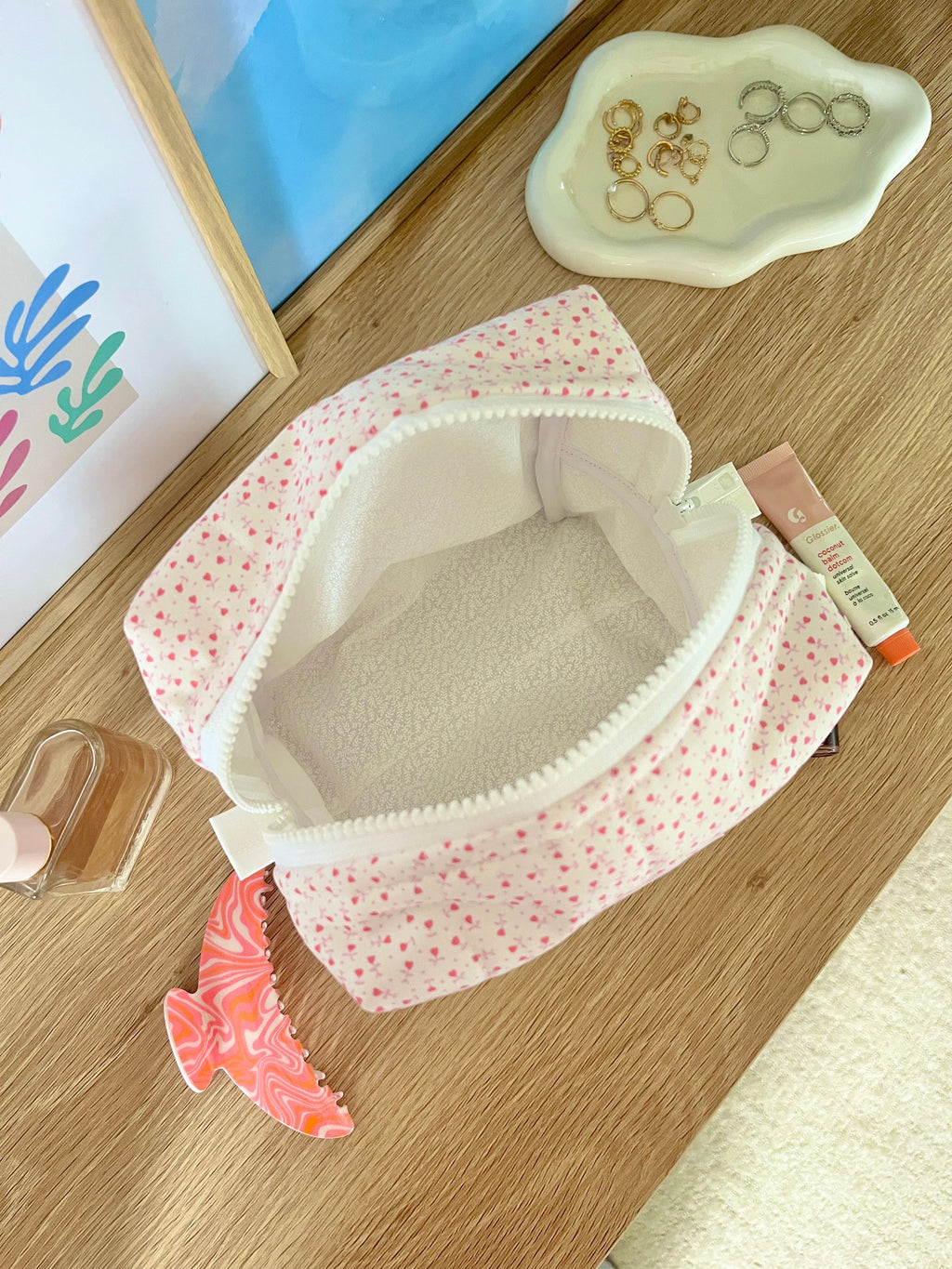 Open medium pink heart-print makeup bag showing white interior lining and zipper edge.