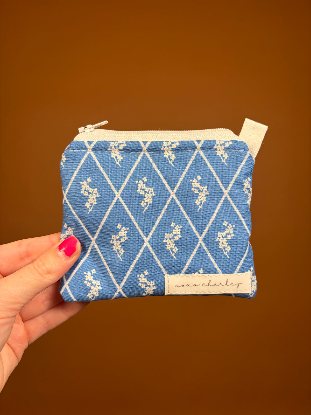 Blue patterned zip keychain wallet with beige label, front view