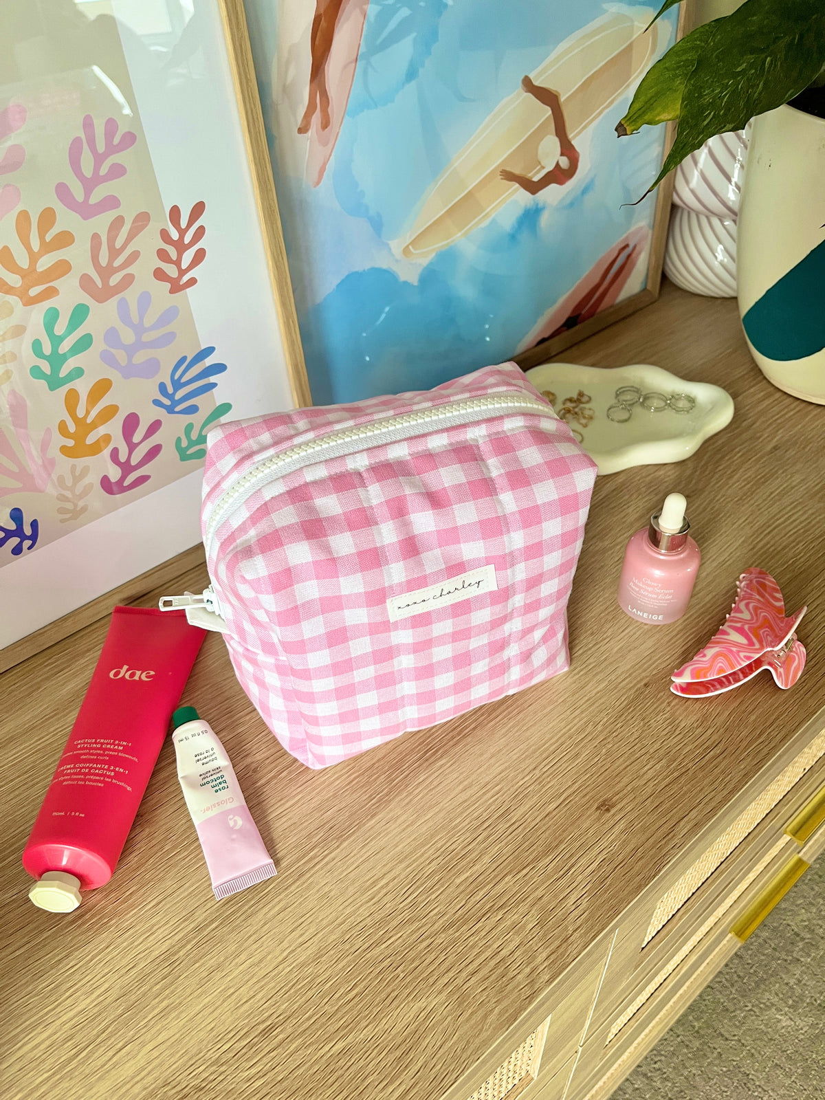 Pink gingham zippered makeup bag with white trim and front label patch