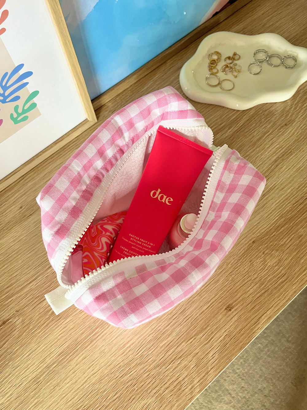 Open pink gingham makeup bag interior with red product pouch visible