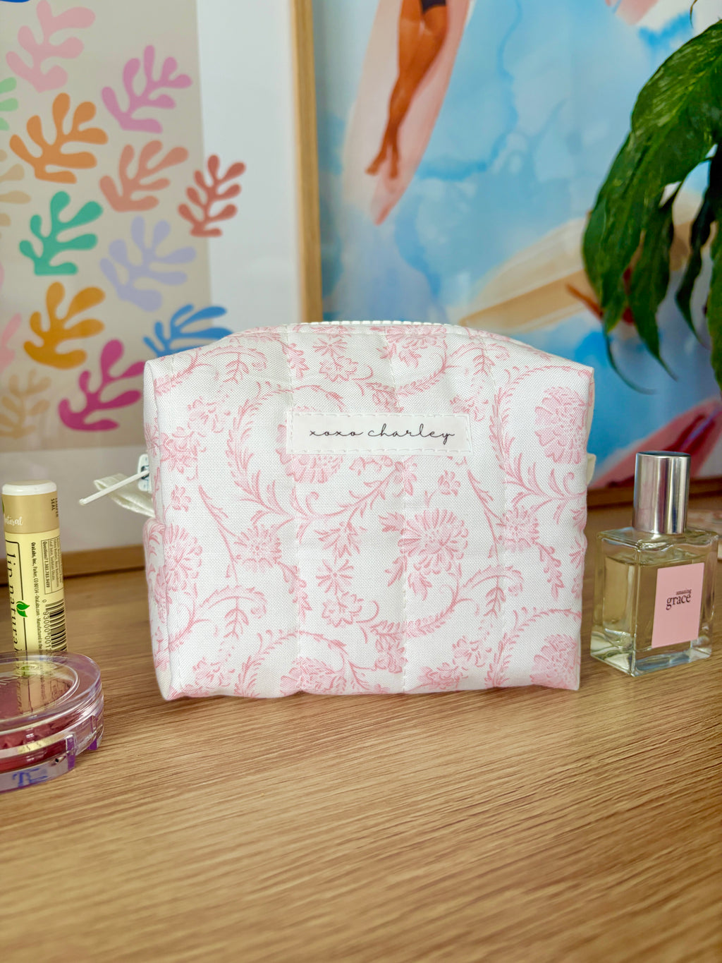 Pink mini makeup bag with pink floral pattern and zip-top closure