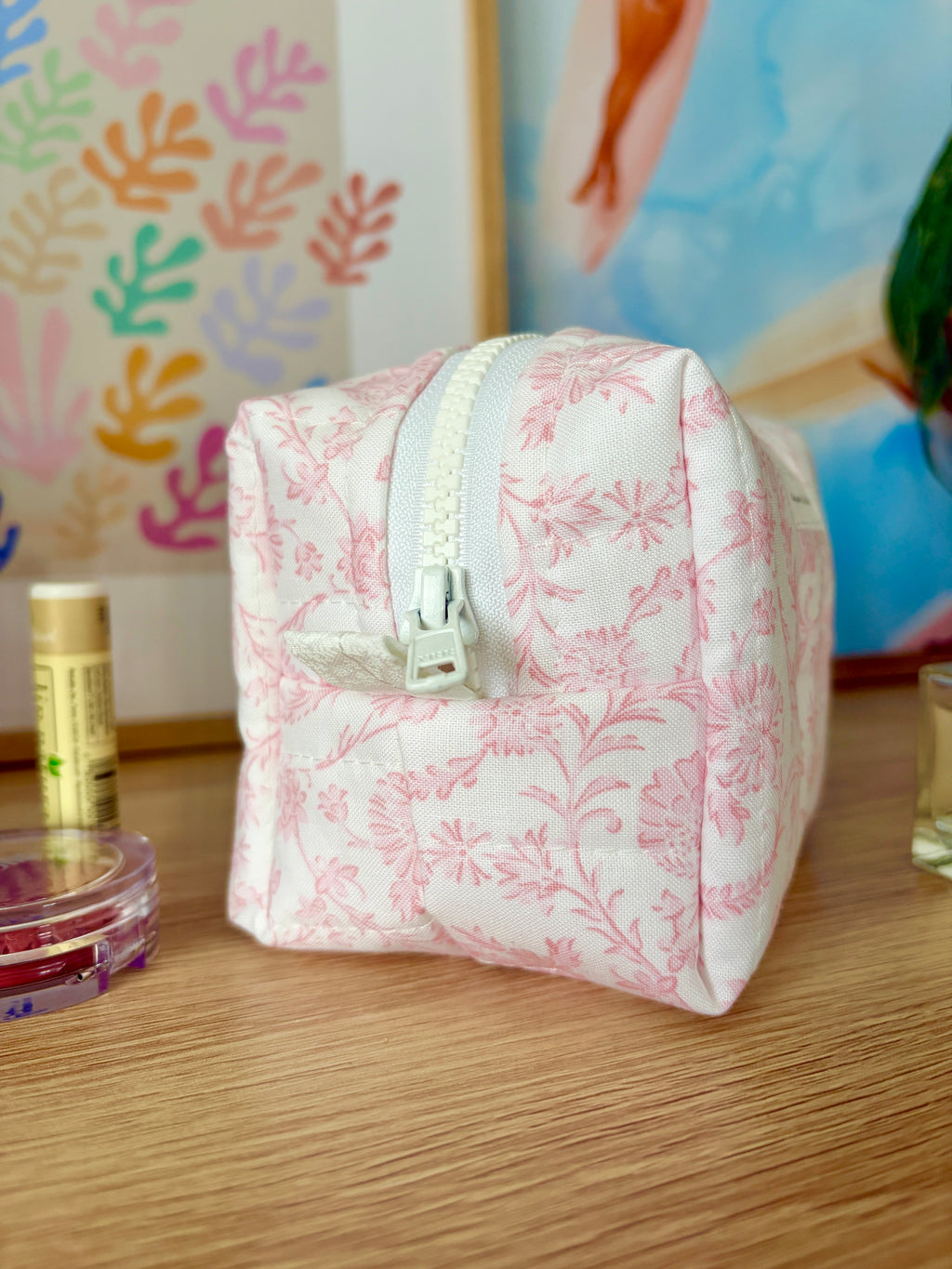 Pink floral mini makeup bag with front zip and short strap handle