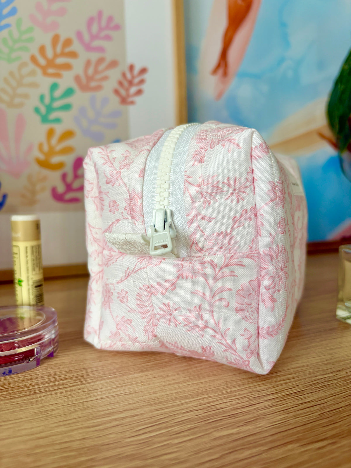Pink floral mini makeup bag with front zip and short strap handle
