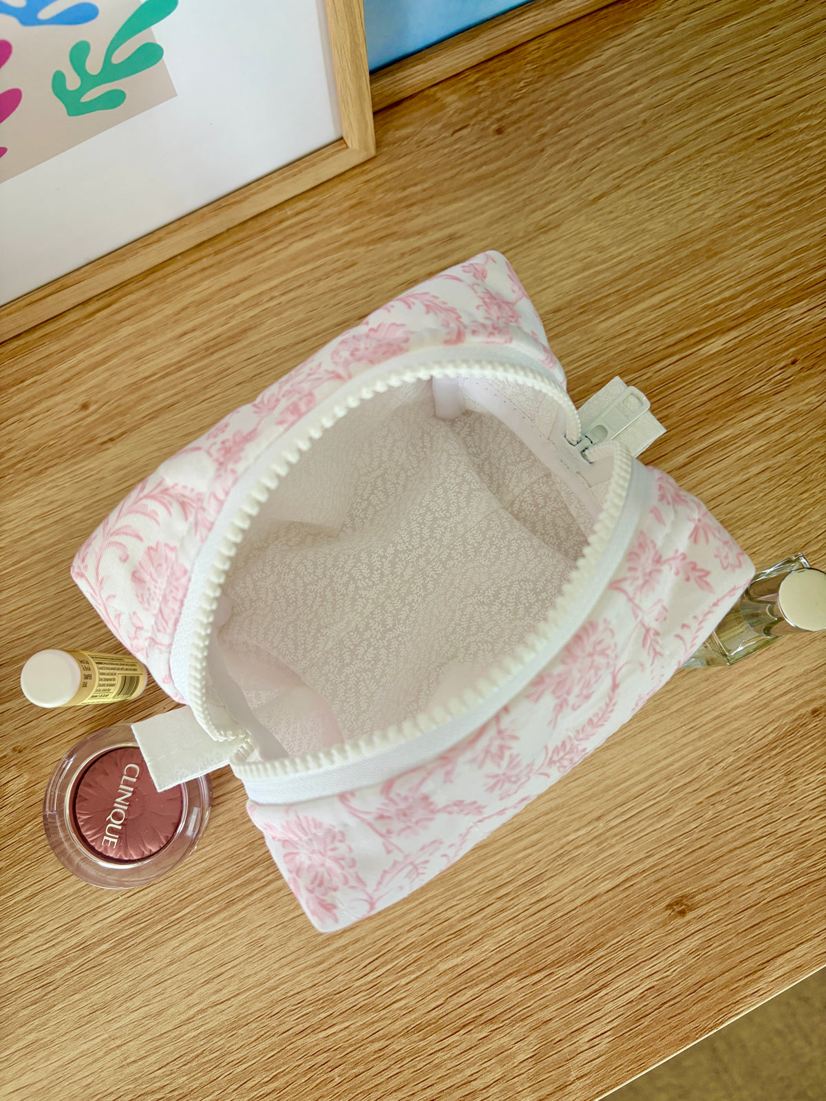 Pink floral mini makeup bag open, showing beige interior and zip opening