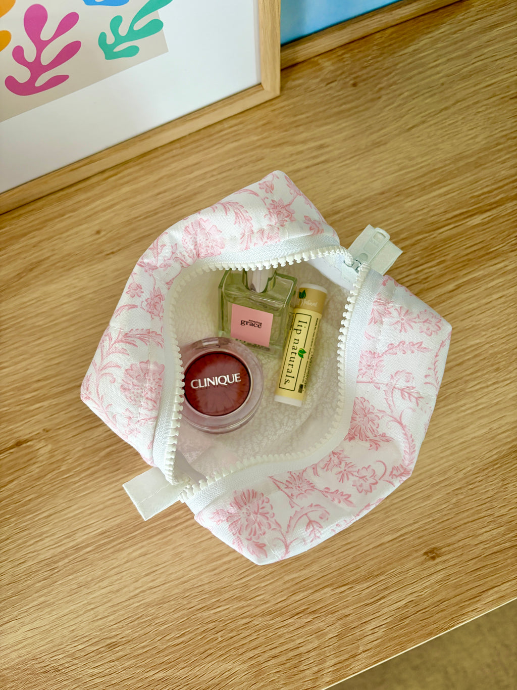Open pink floral mini makeup bag with beige lining and zipper closure
