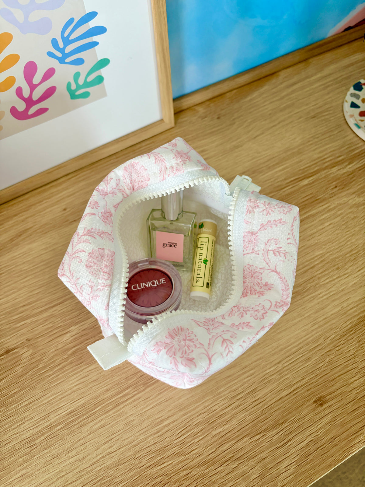Open pink floral mini makeup bag with beige interior panel and zipper top
