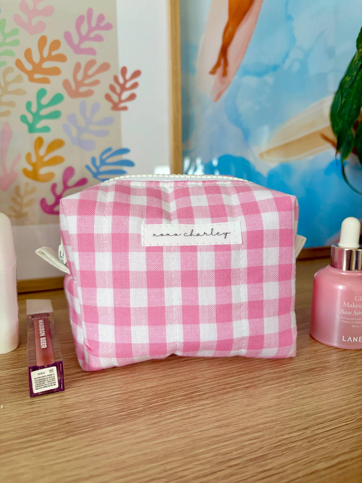 Pink gingham mini makeup bag with white zipper and padded rectangular shape.