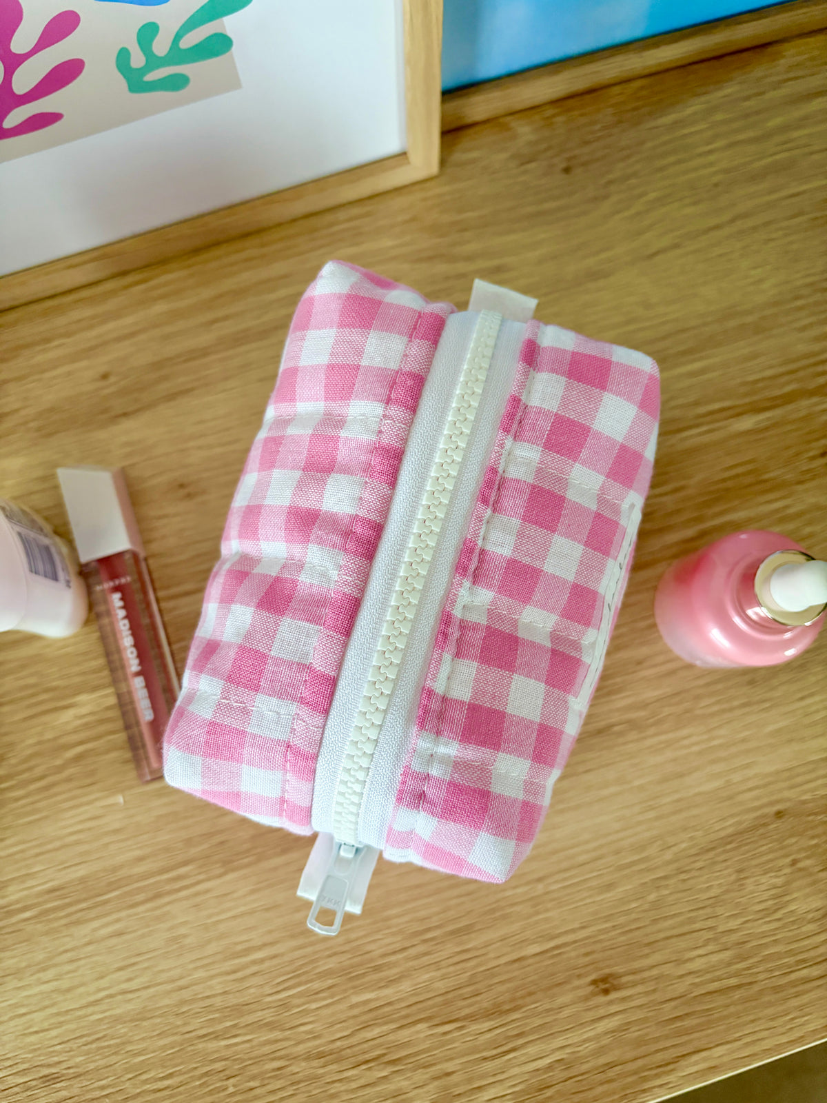 Pink gingham mini makeup bag with white zipper seam and structured look.