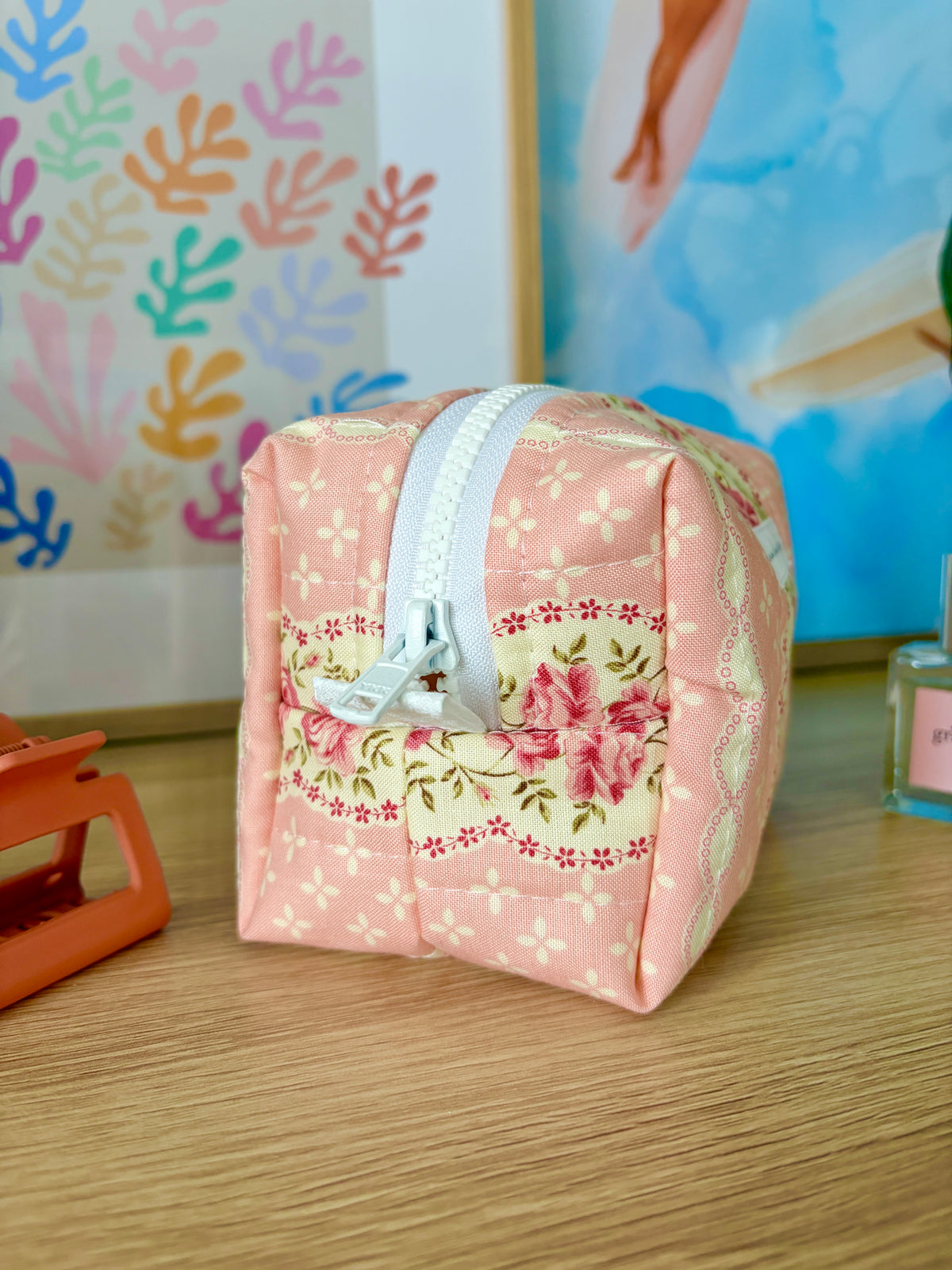 Pink floral mini makeup bag with white zipper closure and top handle