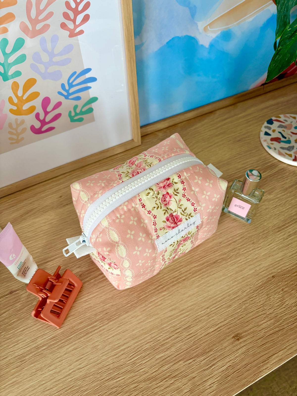 Pink floral mini makeup bag with white zipper and compact rounded shape