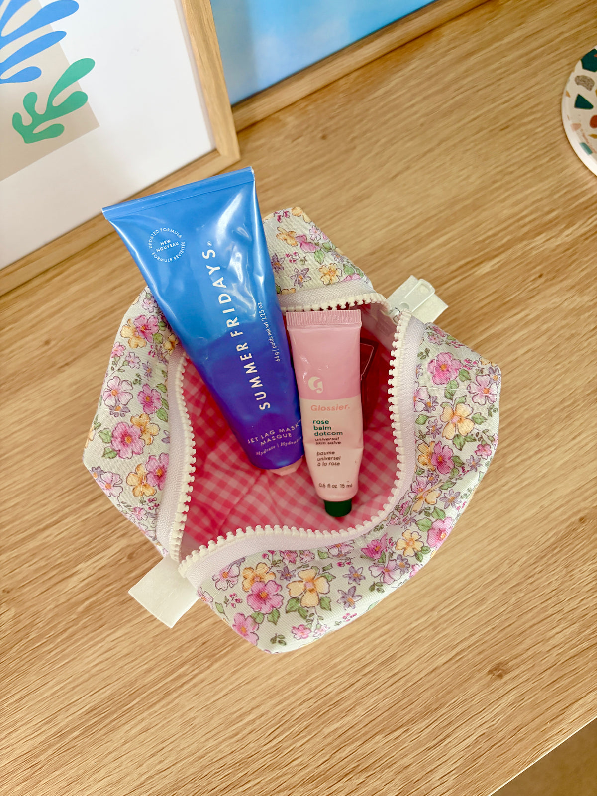 Floral mini makeup bag open; pink gingham lining visible in the zip-top.