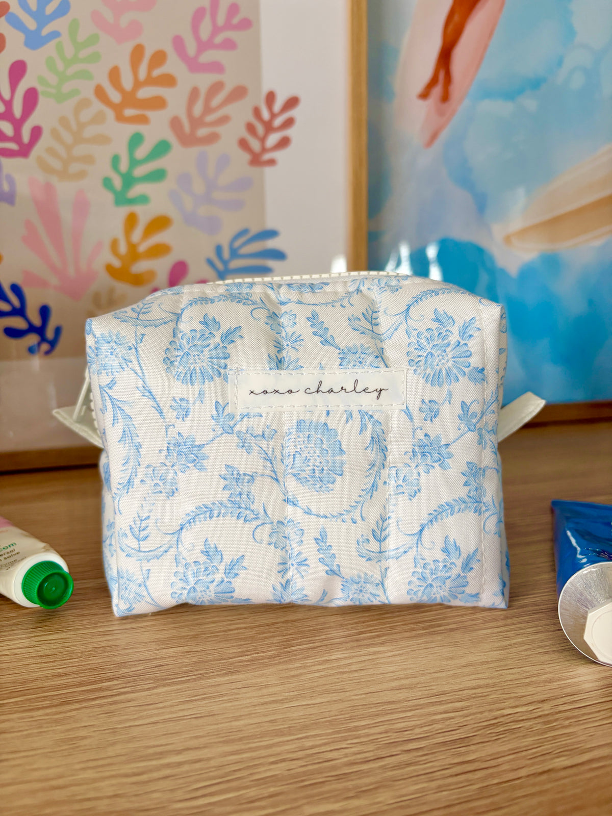 Vintage blue mini makeup bag with white zipper and blue floral fabric, front view.