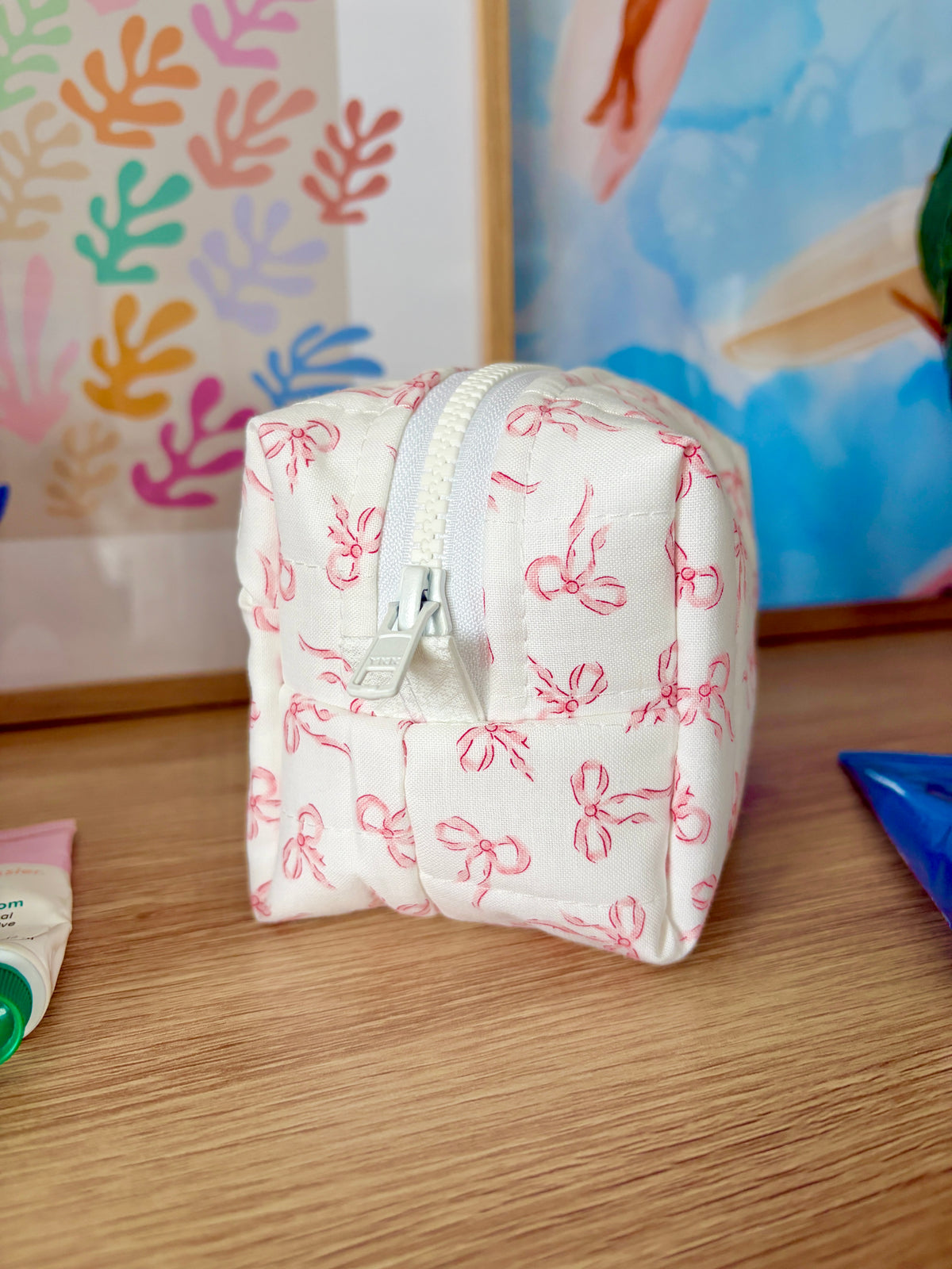Mini makeup bag showing side seam and zip, pink bow print on white fabric