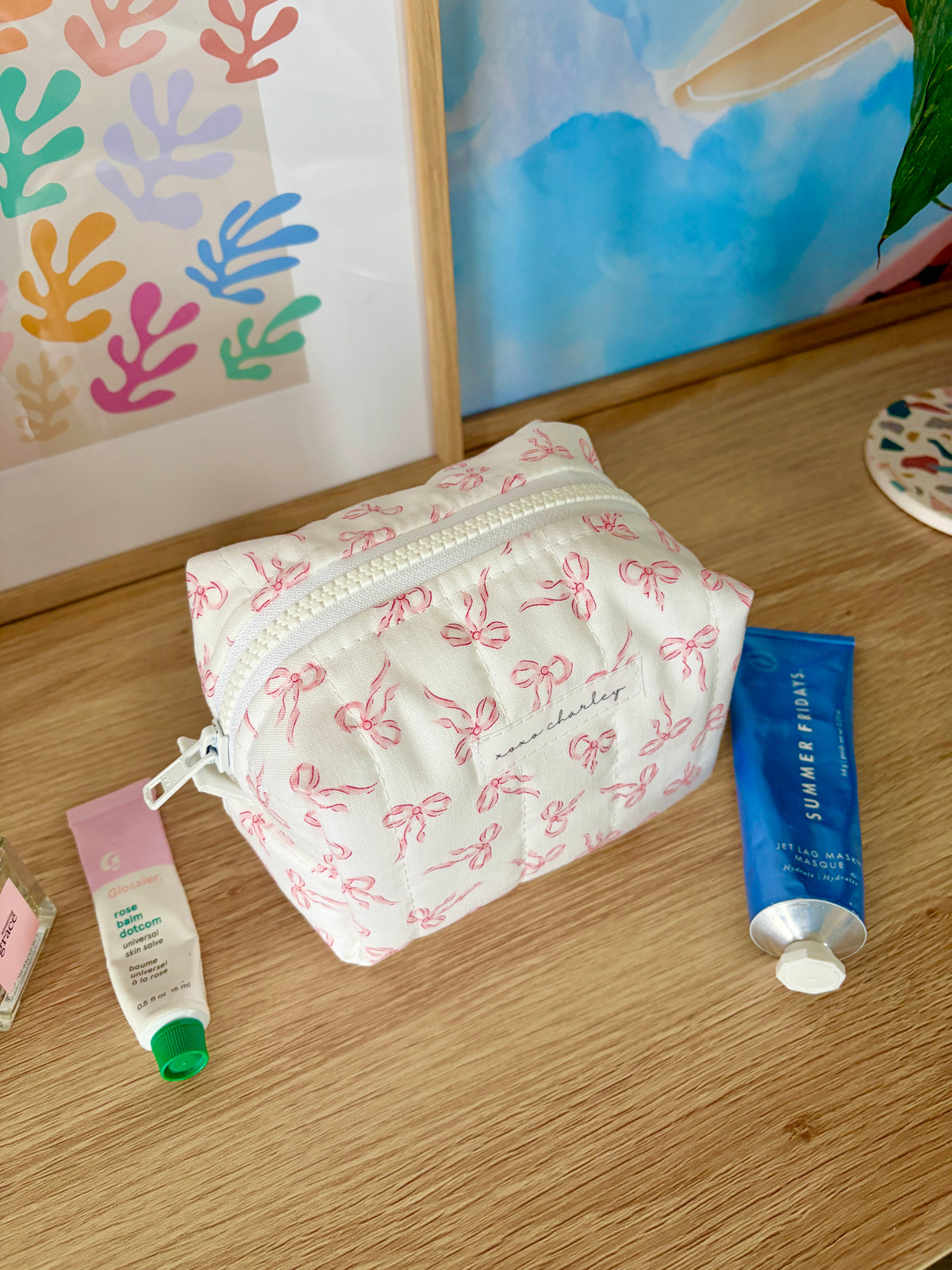 Mini makeup bag with pink bow print and pale gray zipper, front view