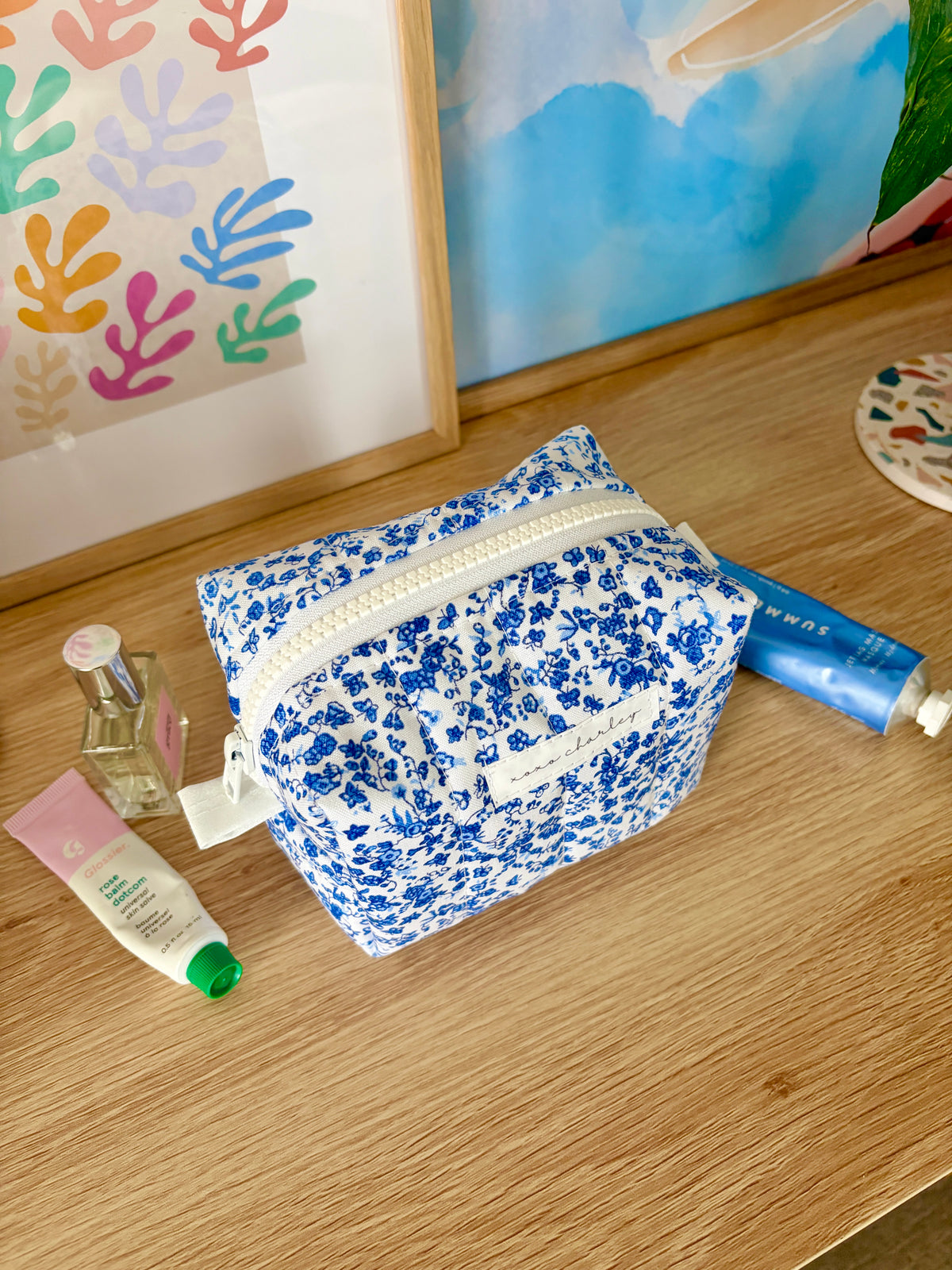 Blue floral mini makeup bag with top zipper, laid open on a table.